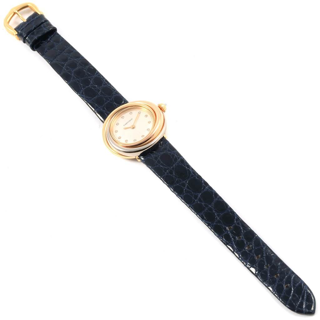 The Cartier Trinity W200246 Women's Yellow Gold Beige Dial W200246 Women's Yellow Gold Beige Dial model watch is shown from a top-down angle, displaying its dial, case, and entire black leather strap.