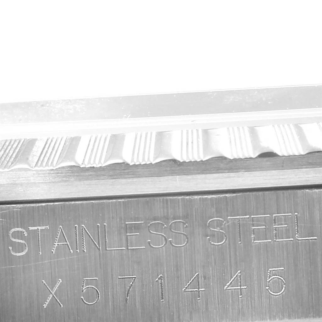 The image shows a close-up angle of the Rolex Datejust 16220 Men's Stainless Steel Silver Dial 16220 Men's Stainless Steel Silver Dial wristwatch bezel and part of the case with "STAINLESS STEEL" and a serial number engraved.