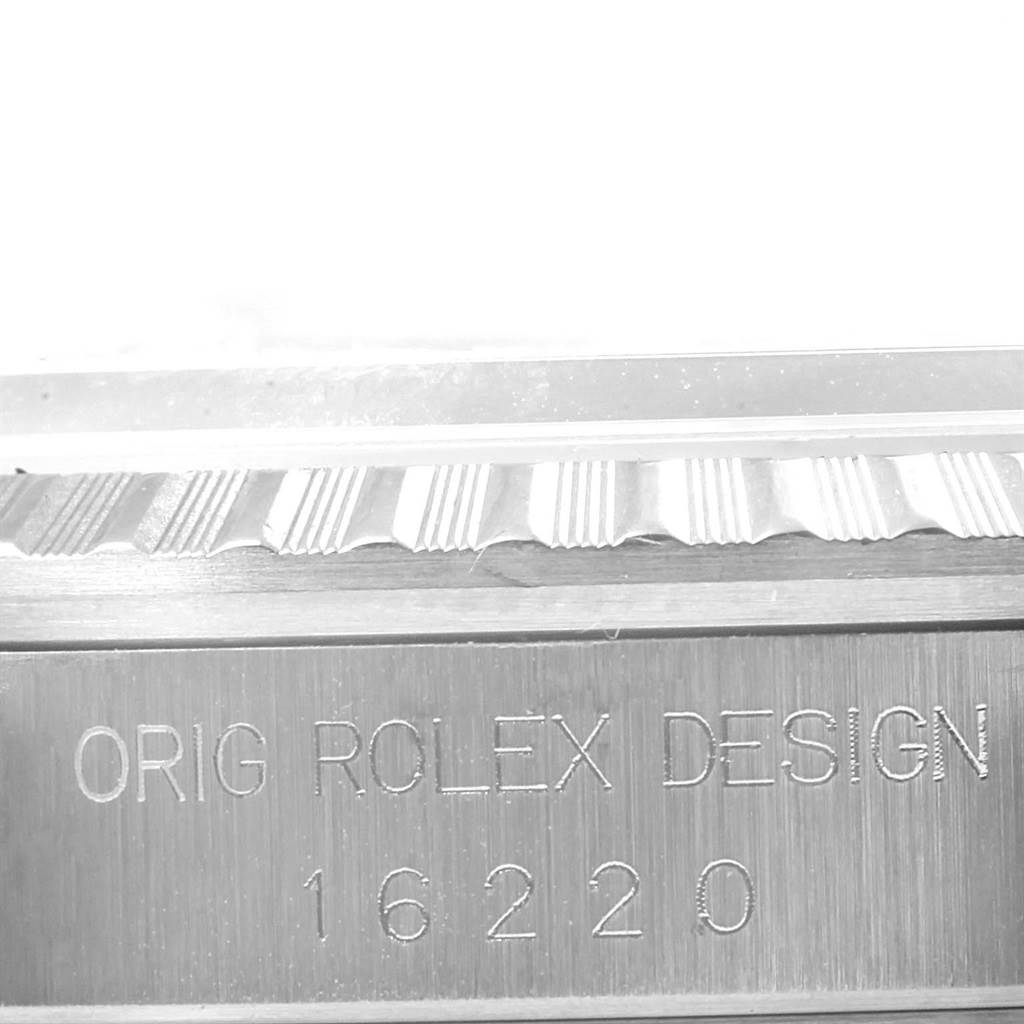 This close-up image shows the engraving "ORIG ROLEX DESIGN 16220" on the side of the bezel of a Rolex Datejust 16220 Men's Stainless Steel Silver Dial 16220 Men's Stainless Steel Silver Dial watch.