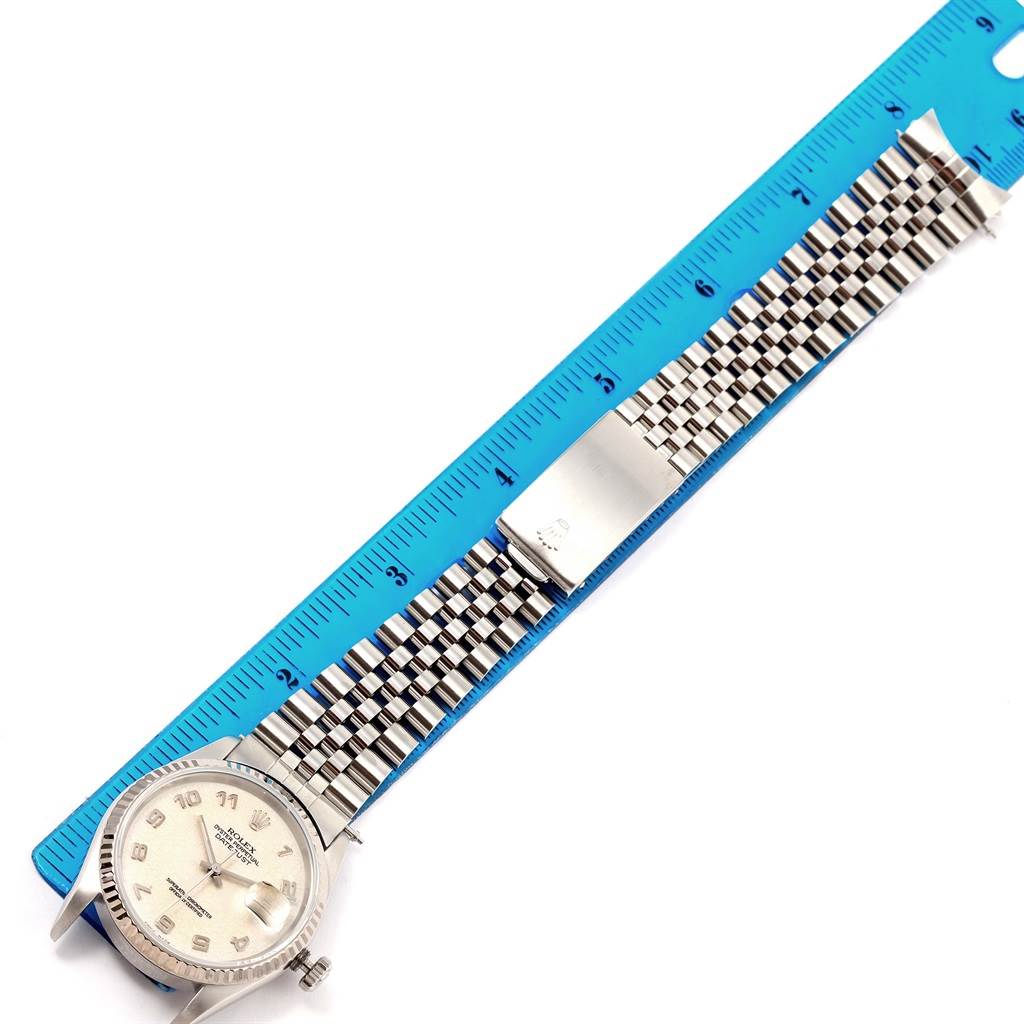 This image shows a Rolex Datejust 16234 Men's Stainless Steel Beige Dial 16234 Men's Stainless Steel Beige Dial watch laid flat next to a ruler, showcasing its face, bracelet, and clasp from the top view.