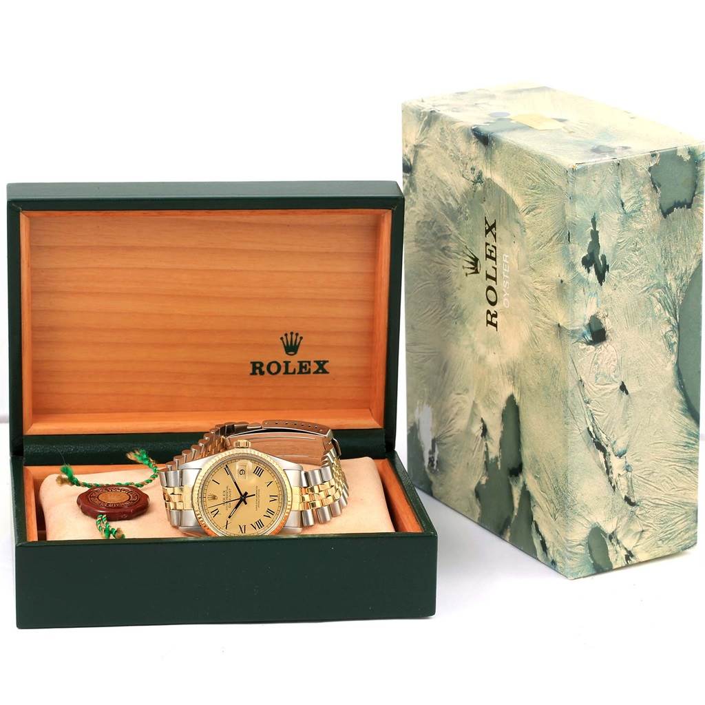 The Rolex Datejust 16013 Men's Stainless Steel Champagne Dial 16013 Men's Stainless Steel Champagne Dial watch is shown in its open green and wooden box with outer packaging beside it.
