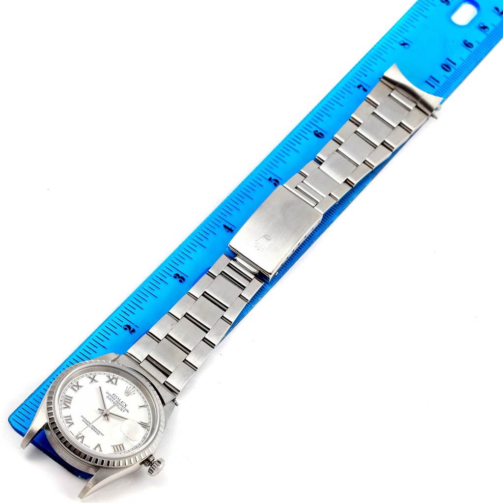 The Rolex Datejust 16220 Men's Stainless Steel White Dial 16220 Men's Stainless Steel White Dial watch is shown flat with a blue ruler, featuring the face, bezel, and full bracelet including the clasp.