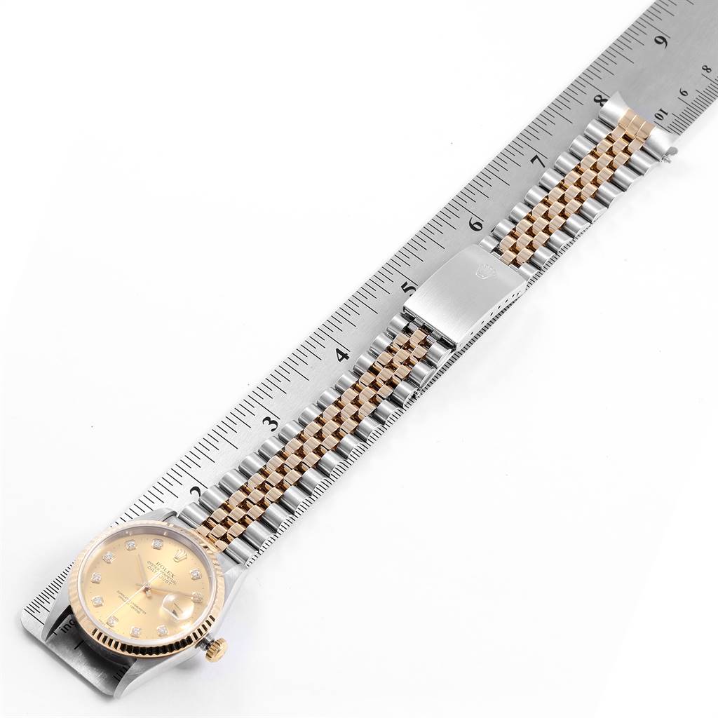 This image shows a Rolex Datejust 16233 Men's Steel and Gold (two tone) Champagne Dial 16233 Men's Steel and Gold (two tone) Champagne Dial watch and its two-tone bracelet alongside a ruler for measurement.