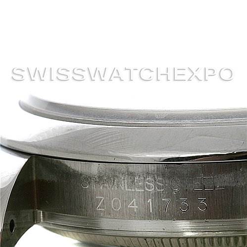 The image shows a close-up of the side of a Rolex Datejust 116200-BKRJ Men's Stainless Steel Black Dial 116200-BKRJ Men's Stainless Steel Black Dial watch, specifically highlighting the stainless steel case and serial number.