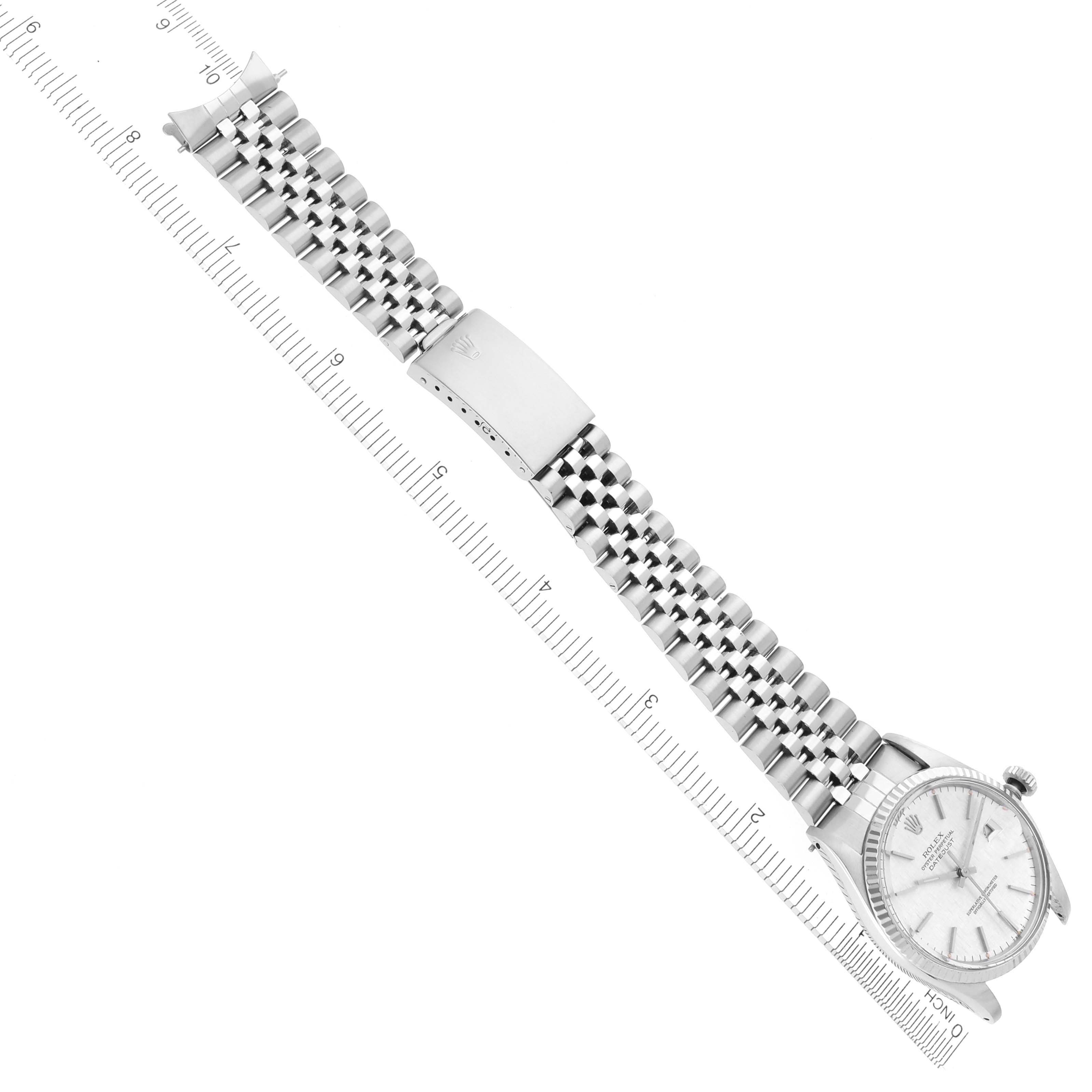 The Rolex Datejust 16014 Men's Stainless Steel Silver Dial 16014 Men's Stainless Steel Silver Dial watch is shown at an angle, displaying the dial, bracelet, and clasp alongside a ruler for scale.