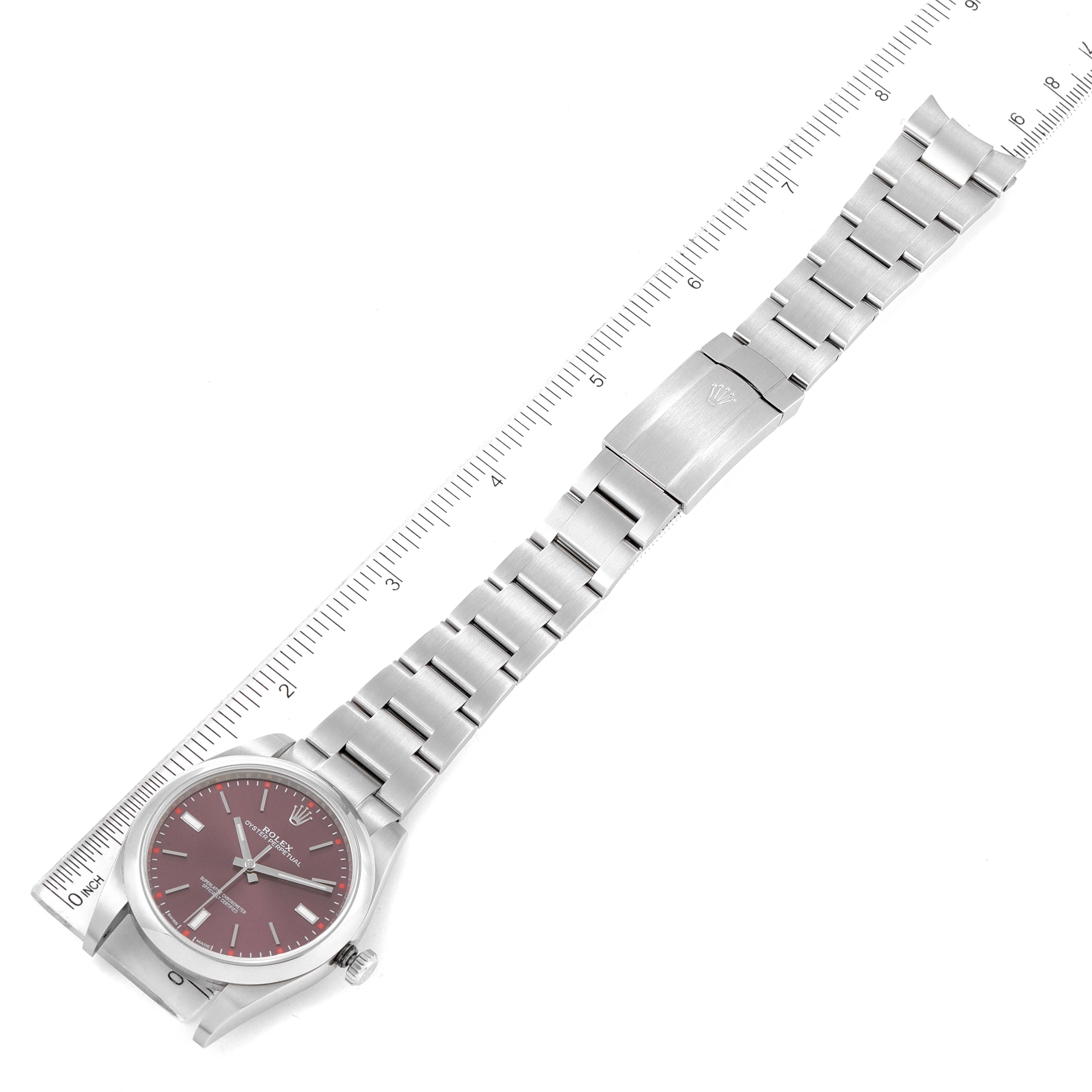 This image shows a top-down view of a Rolex Oyster Perpetual 114300 Men's Stainless Steel Burgundy Dial 114300 Men's Stainless Steel Burgundy Dial watch with a ruler alongside, displaying the bracelet and face.