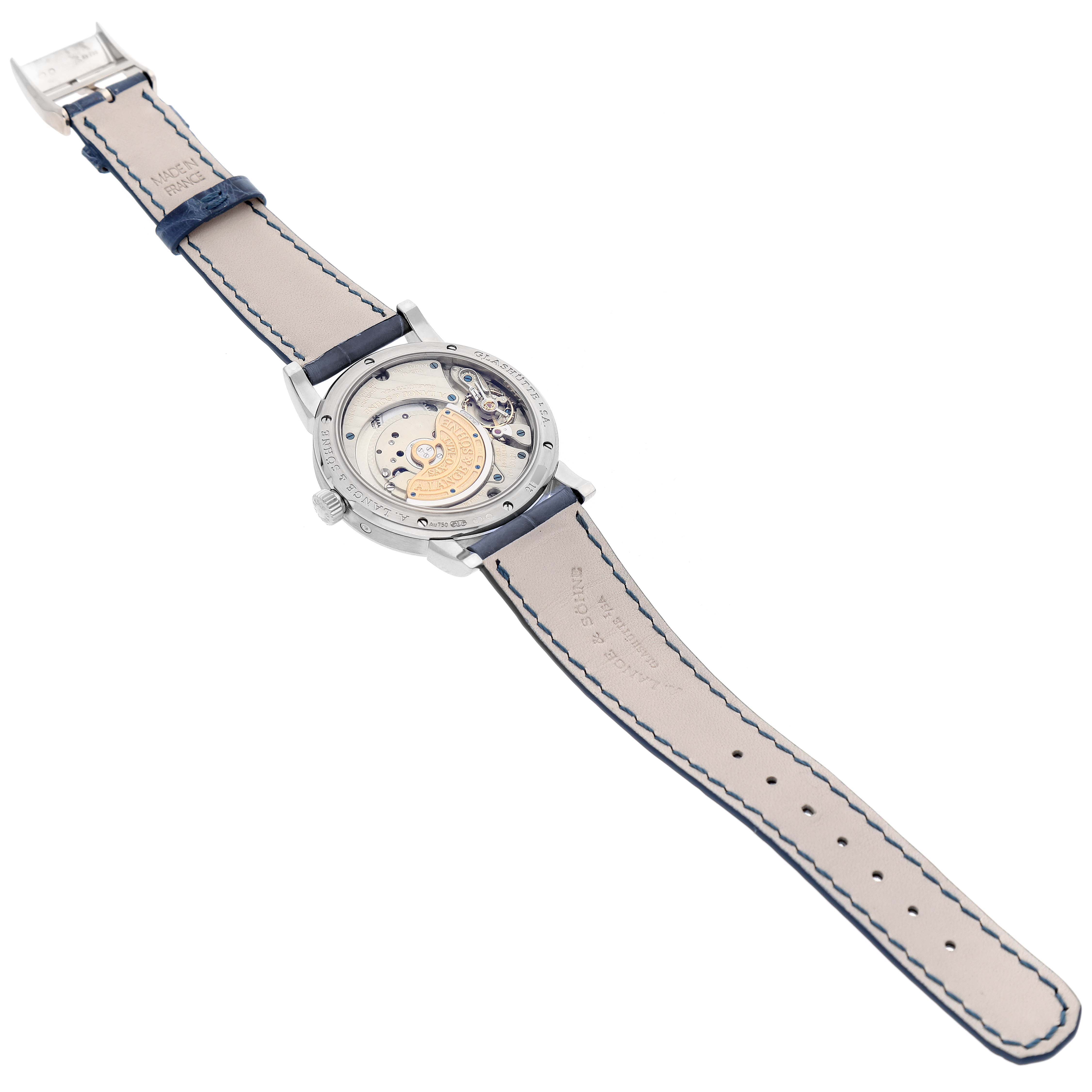 The image shows the back view of the A. Lange & Sohne Saxonia 330.026 Men's White Gold Silver Dial model, highlighting its intricate movement and leather strap.