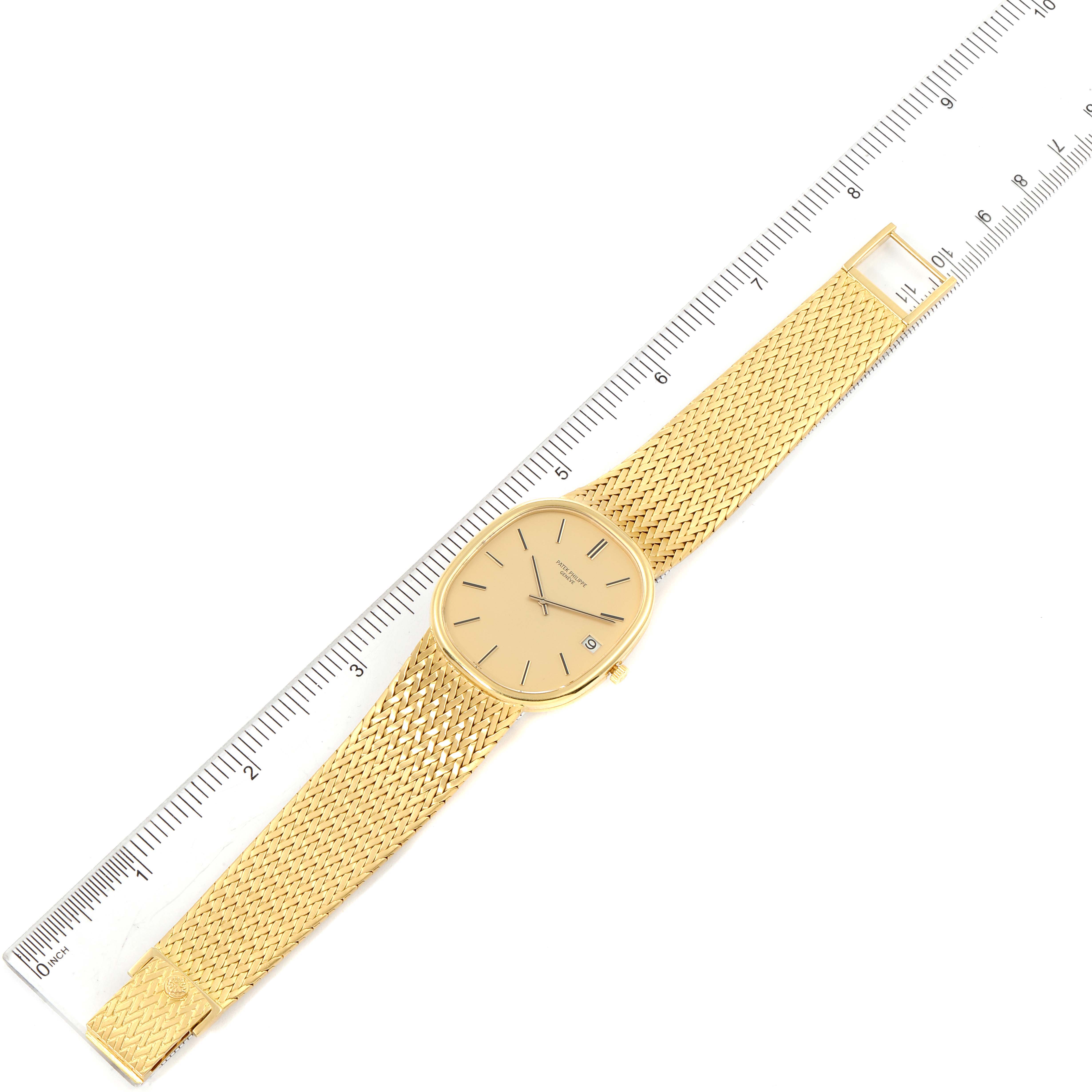 The image shows an overhead view of the Patek Philippe Golden Ellipse 3605 Men's Yellow Gold Champagne Dial 3605 Men's Yellow Gold Champagne Dial watch, including its face and golden mesh strap, placed next to a ruler.