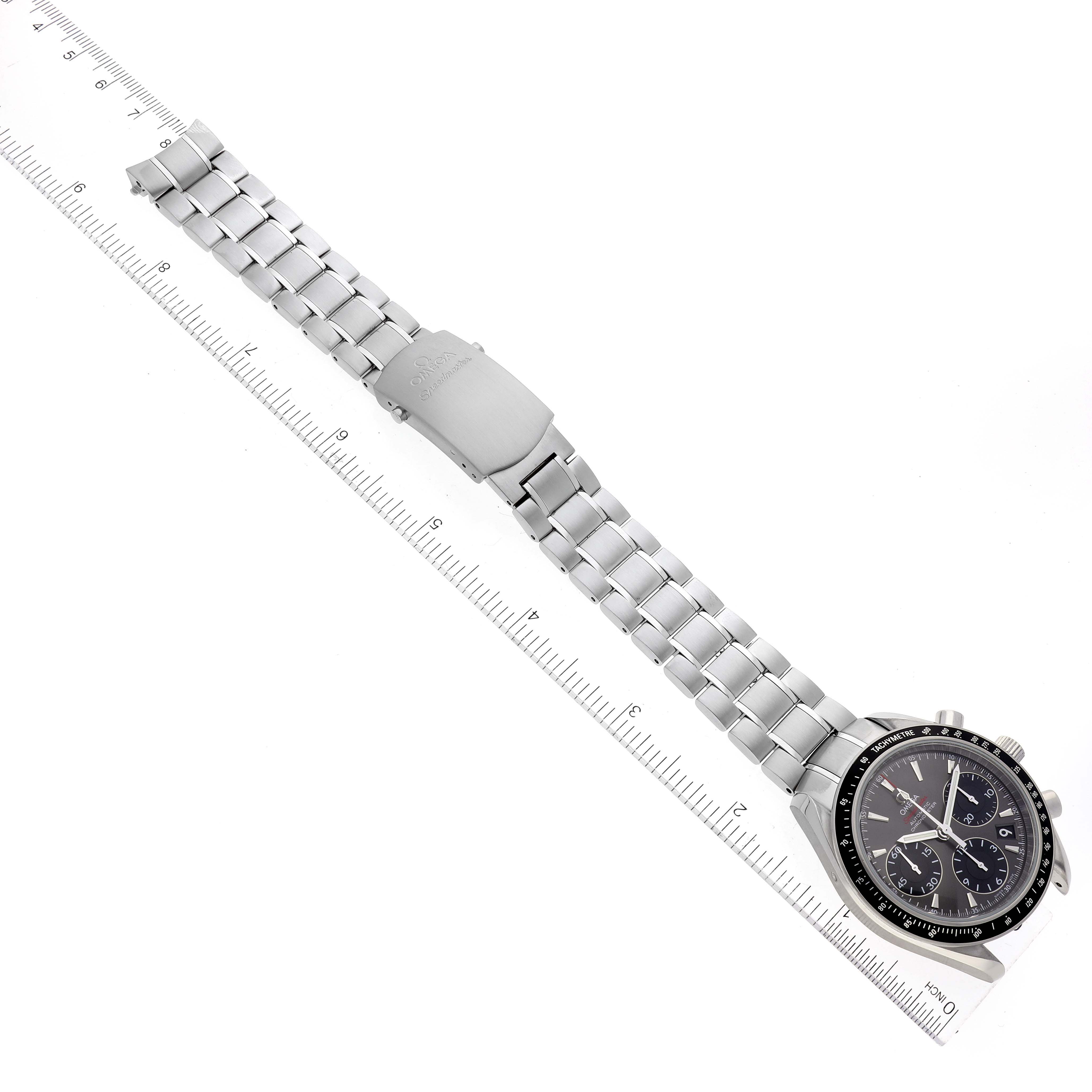 The image shows an Omega Speedmaster 323.30.40.40.06.001 Men's Stainless Steel Grey Dial 323.30.40.40.06.001 Men's Stainless Steel Grey Dial watch with a stainless steel bracelet, laid flat next to a ruler for measurement.