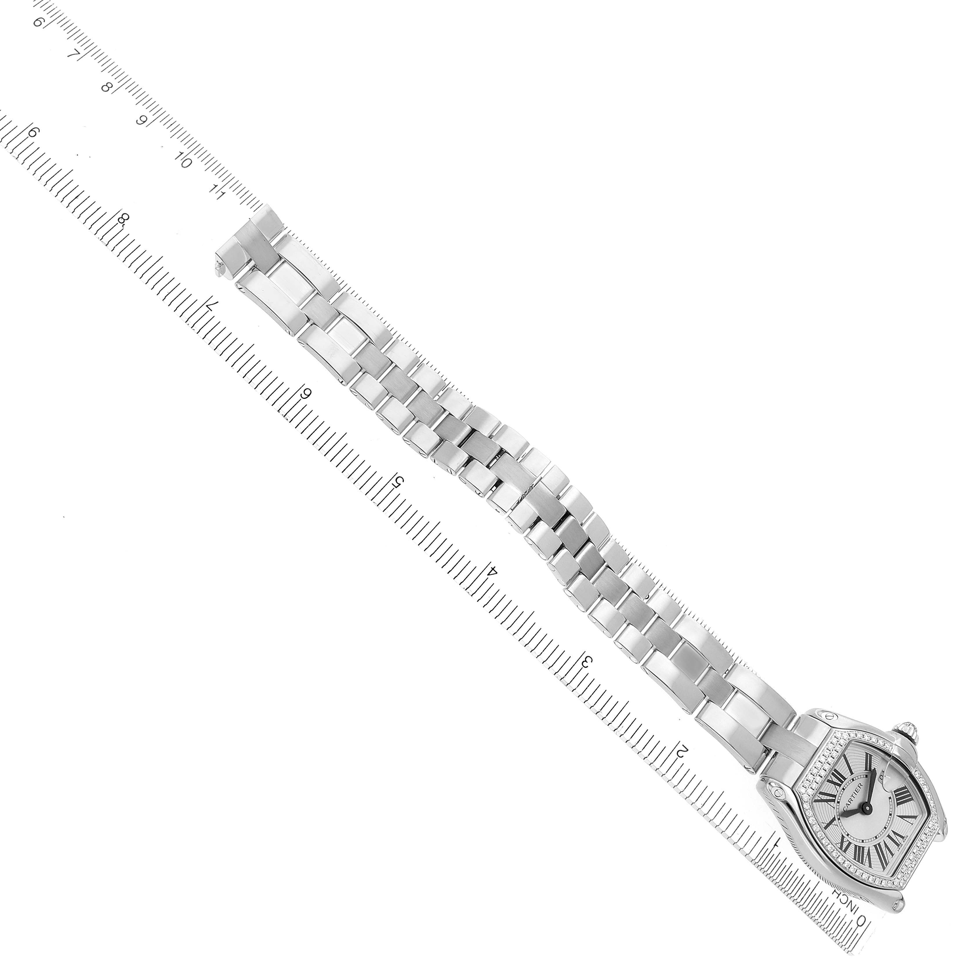 The Cartier Roadster WE5002X2 Women's White Gold Silver Dial WE5002X2 Women's White Gold Silver Dial watch is shown diagonally, highlighting its face and bracelet against a ruler for scale.