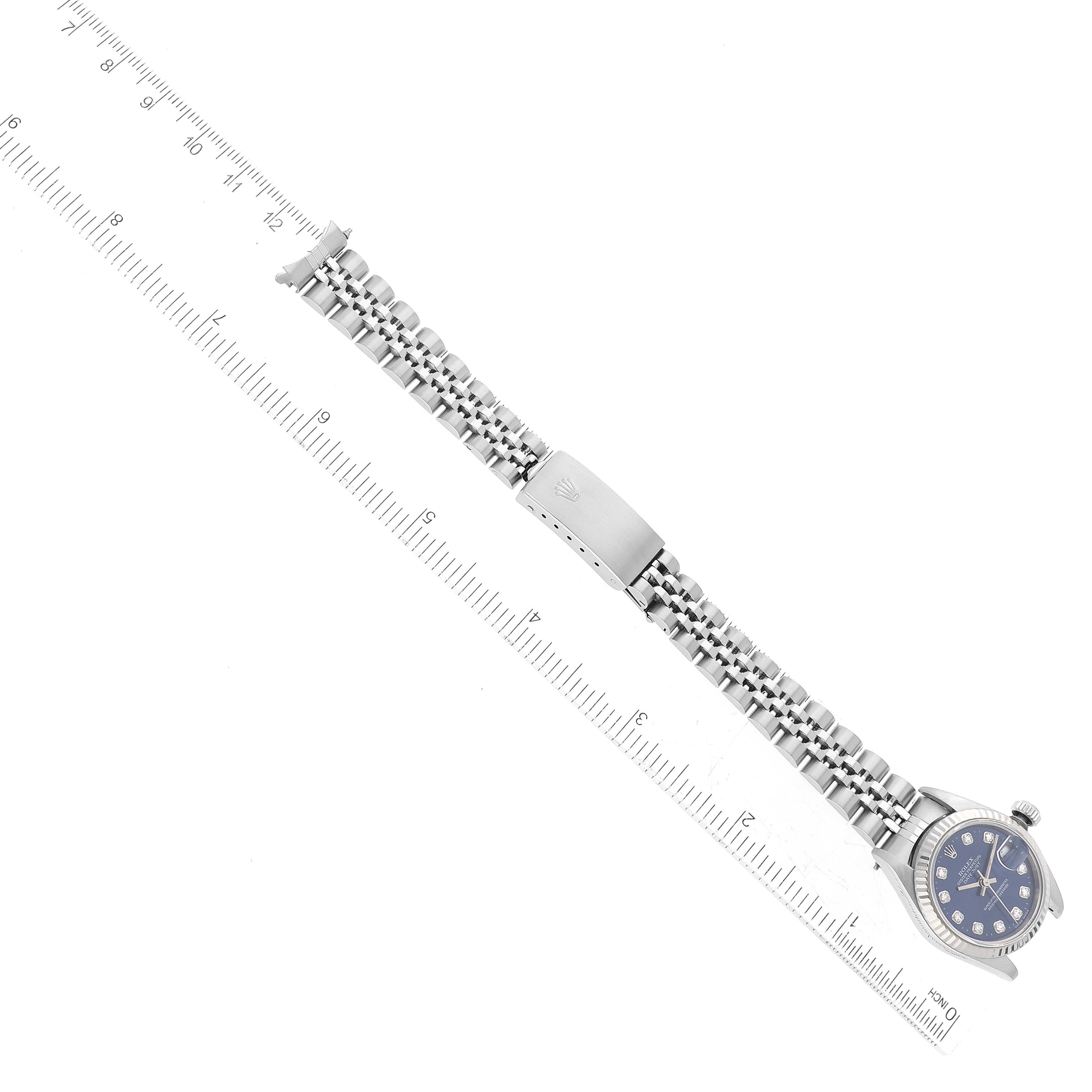 This image shows a Rolex Datejust 79174G Women's Stainless Steel Blue Dial 79174G Women's Stainless Steel Blue Dial watch positioned flat with its bracelet and clasp extended, alongside a ruler for scale.