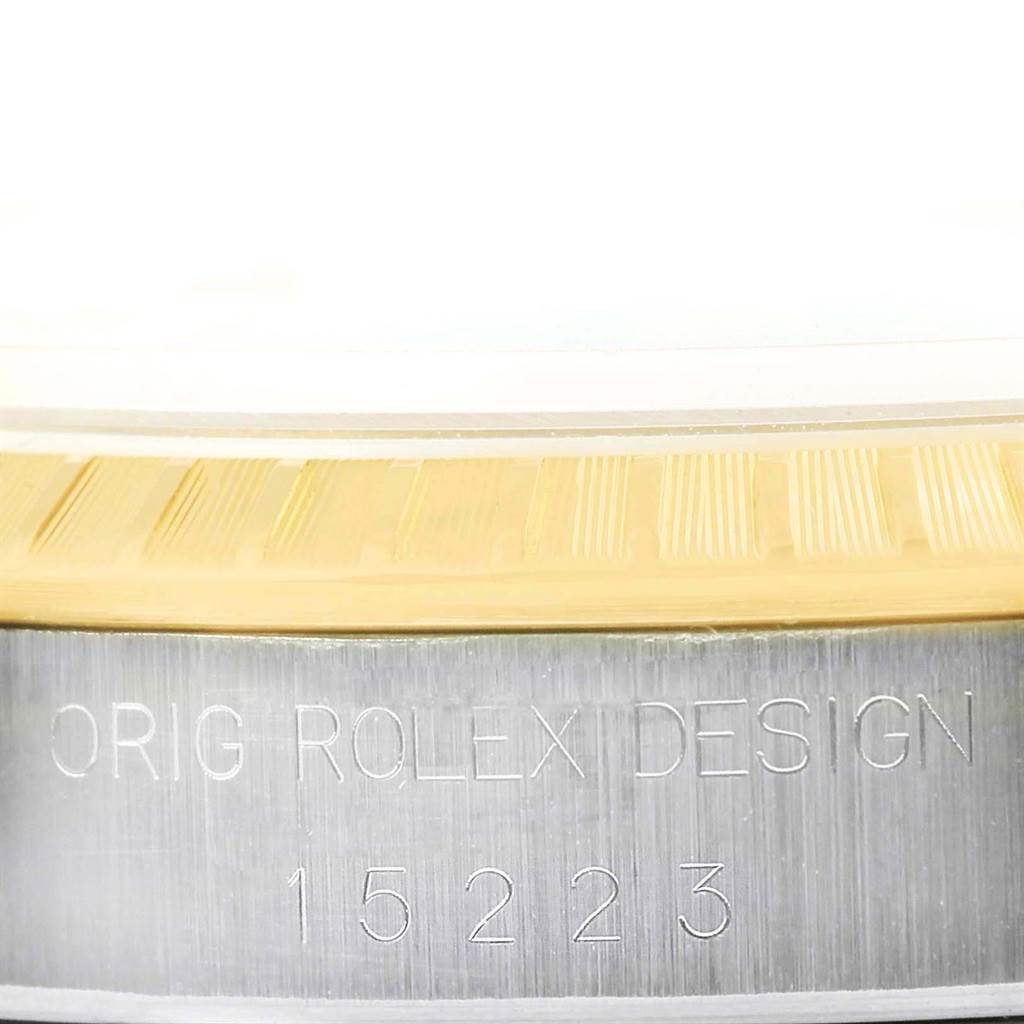 This image shows a close-up of the side view of a Rolex Date 15223 Men's Steel and Gold (two tone) White Dial 15223 Men's Steel and Gold (two tone) White Dial model, featuring the serial number and "ORIG ROLEX DESIGN" engraving.