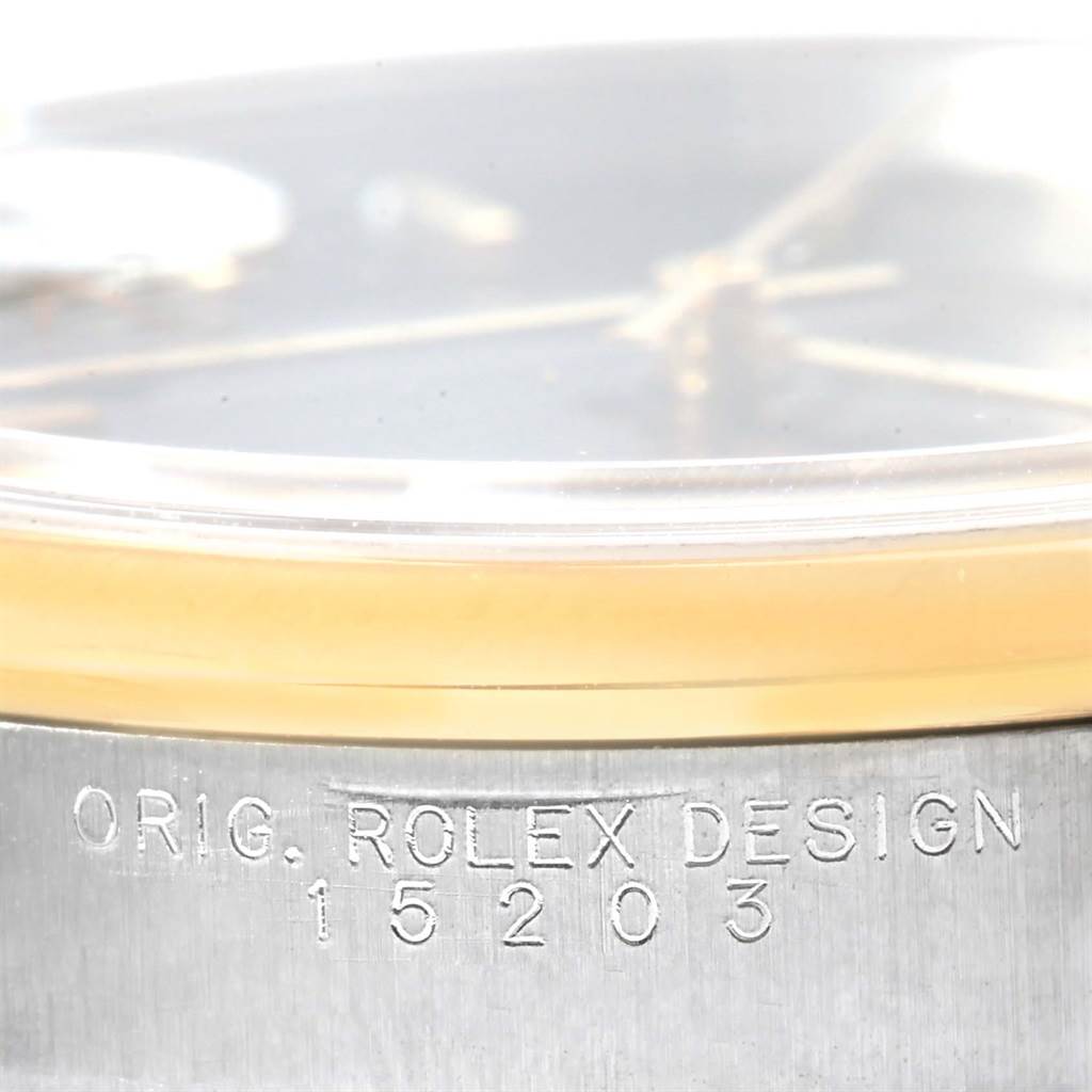 This close-up image shows the side of a Rolex Date 15203 Men's Steel and Gold (two tone) Black Dial 15203 Men's Steel and Gold (two tone) Black Dial model, emphasizing the engraved serial number and "ORIG. ROLEX DESIGN" text.