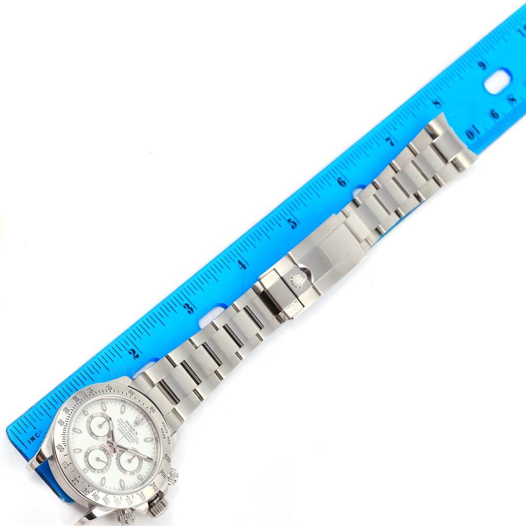 The image shows a Rolex Daytona 116520 Men's Stainless Steel White Dial 116520 Men's Stainless Steel White Dial watch laid flat alongside a blue ruler, displaying the face and metal bracelet from an overhead angle.