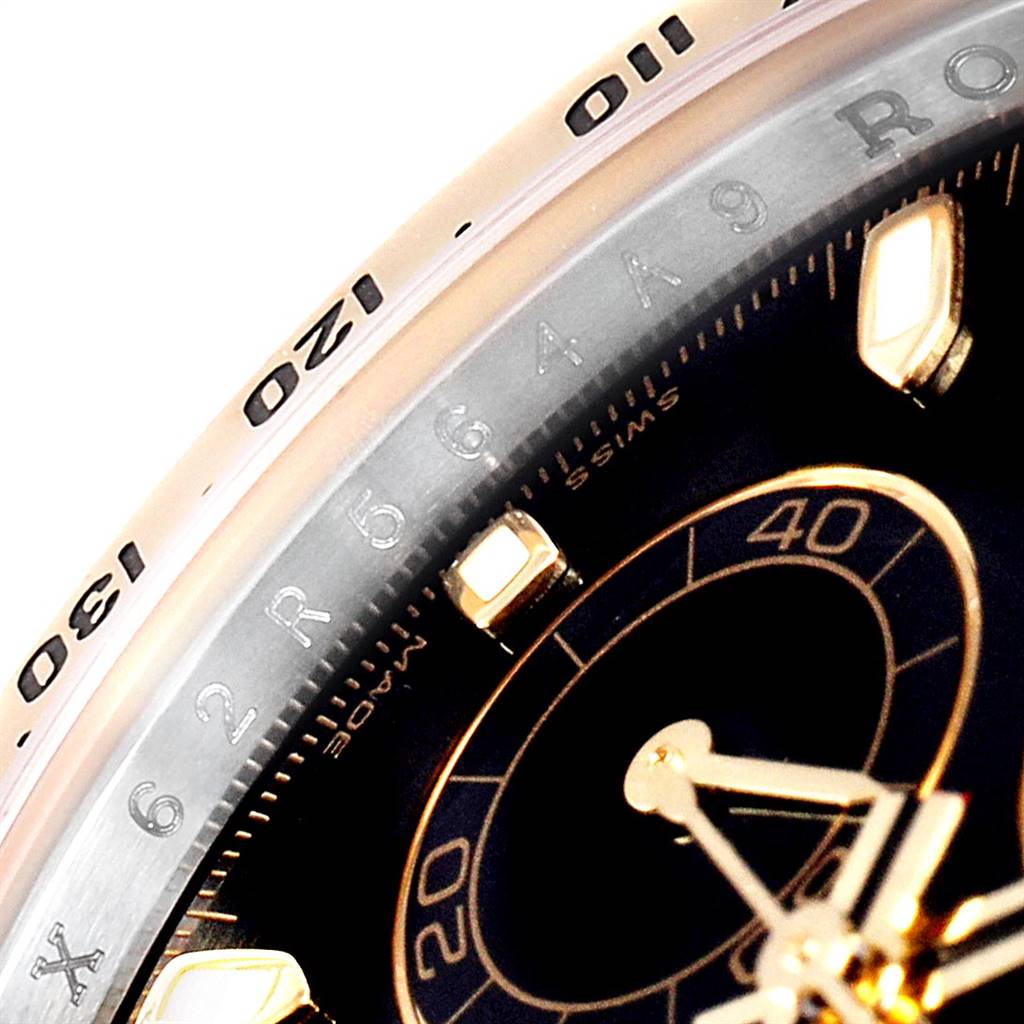 This close-up of the Rolex Daytona 116523 Men's Steel and Gold (two tone) Black Dial 116523 Men's Steel and Gold (two tone) Black Dial watch shows a portion of the bezel and the dial with intricate markings.