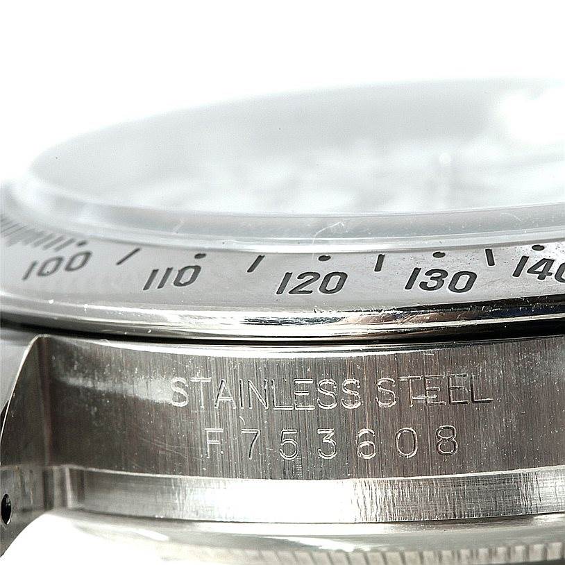 The close-up image shows part of the bezel and case of a Rolex Daytona 116520 Men's Stainless Steel White Dial 116520 Men's Stainless Steel White Dial watch, highlighting its stainless steel and engraved serial number.