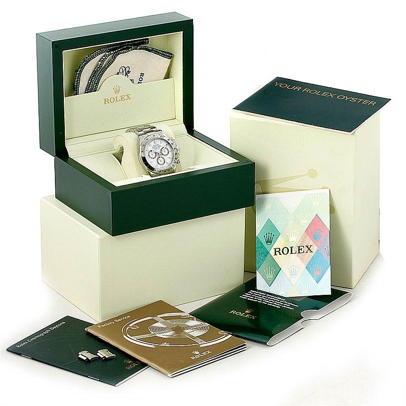 The image shows a Rolex Daytona 116520 Men's Stainless Steel White Dial 116520 Men's Stainless Steel White Dial watch at a three-quarter angle with its box and accompanying booklets and accessories.