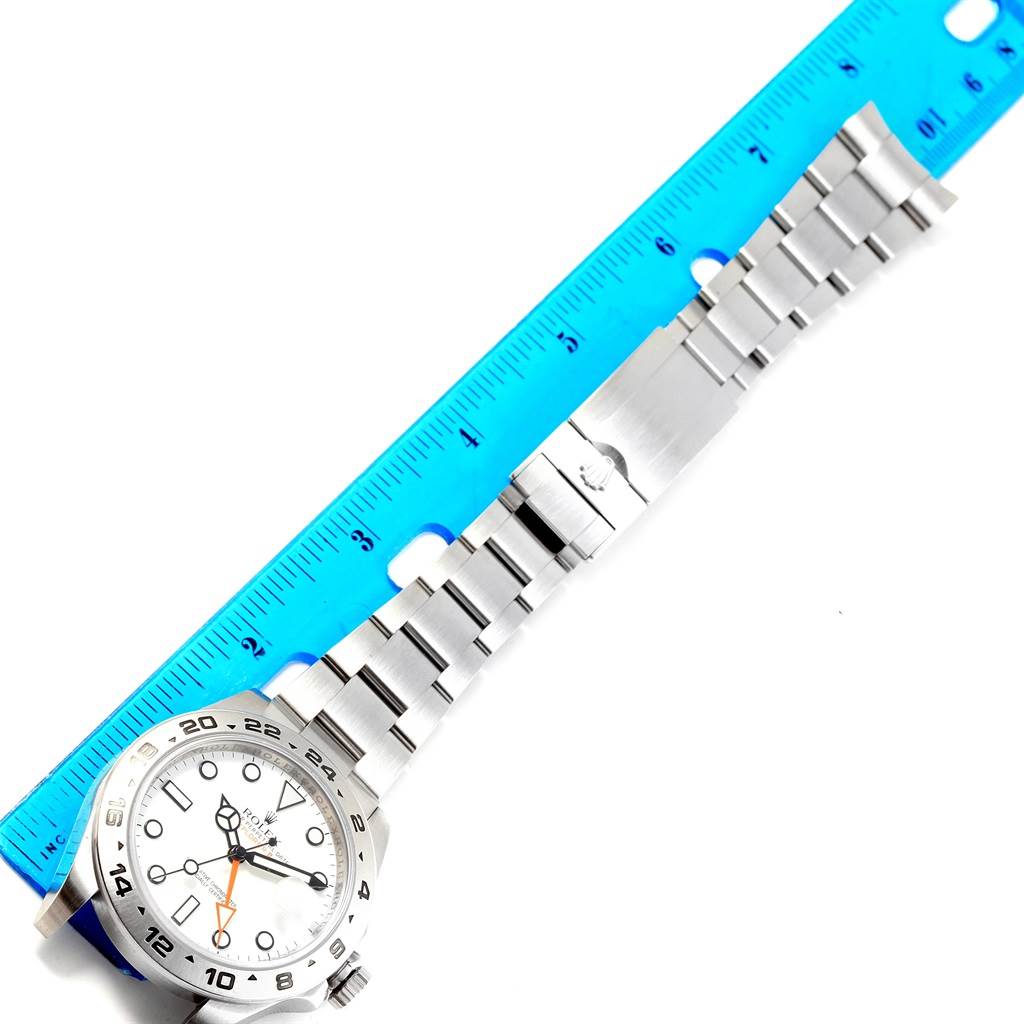 The image shows a top-down view of a Rolex Explorer 216570 Men's Stainless Steel White Dial 216570 Men's Stainless Steel White Dial watch, highlighting its dial, bezel, and bracelet alongside a ruler.