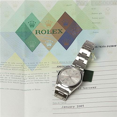 The image shows a Rolex Air-King 1400 Men's Stainless Steel Silver Dial 1400 Men's Stainless Steel Silver Dial watch placed at an angle, showcasing its dial and bracelet, along with its certification papers.