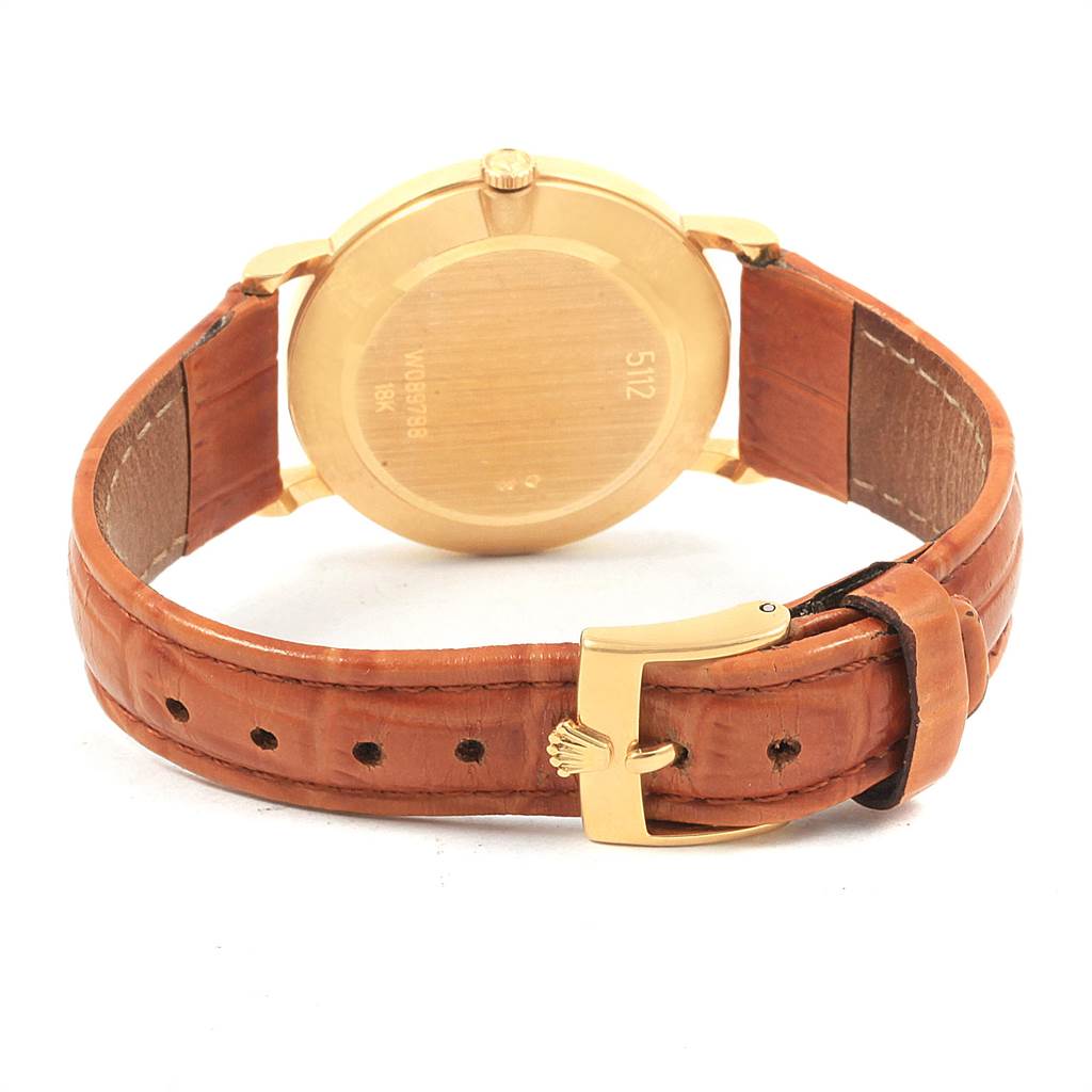 The image shows a rear view of a Rolex Cellini 5112 Men's Yellow Gold Beige Dial 5112 Men's Yellow Gold Beige Dial watch featuring its gold case back and brown leather strap with buckle.