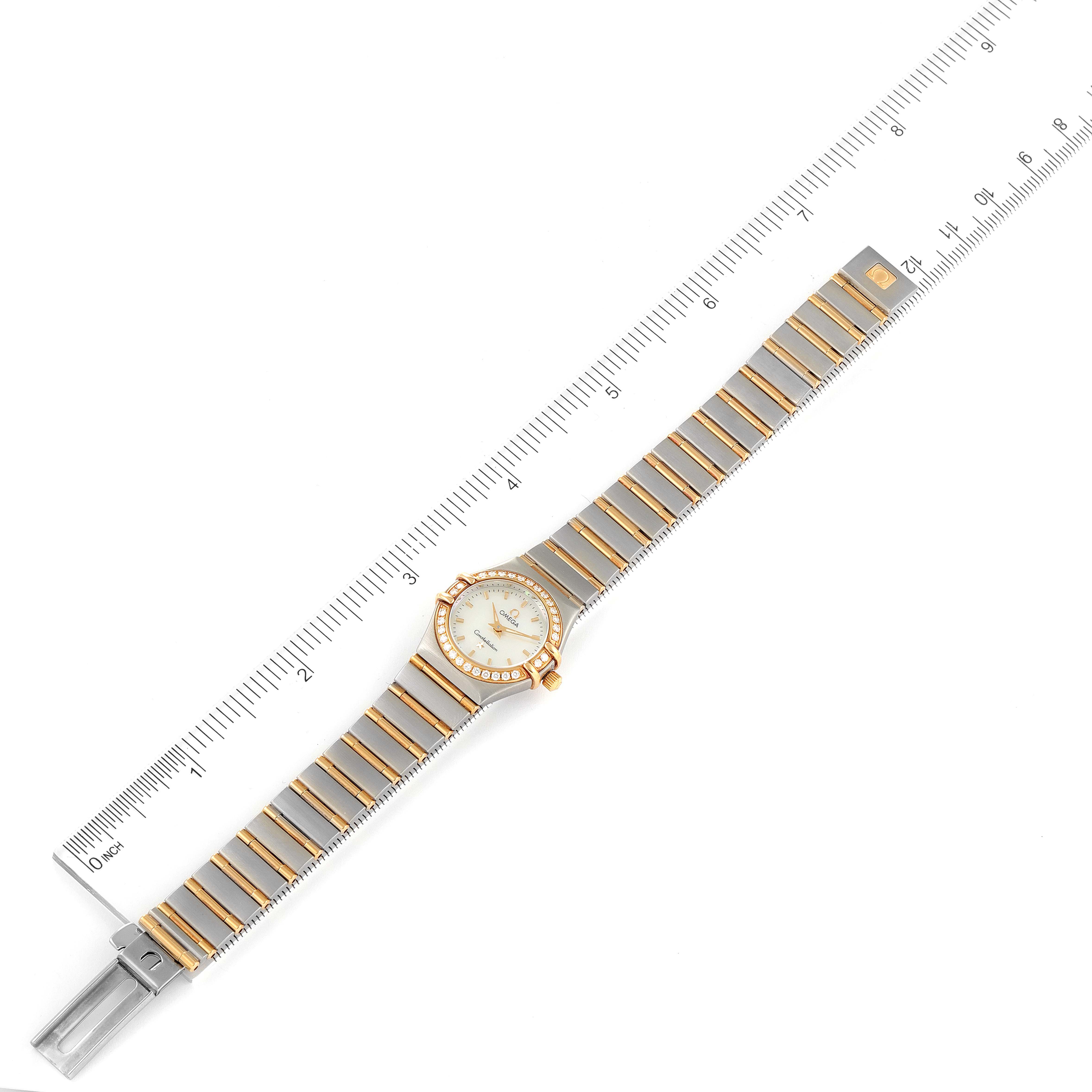 The Omega 1267.70.00 Women's Steel and Gold (two tone) Mother of Pearl Dial 1267.70.00 Women's Steel and Gold (two tone) Mother of Pearl Dial Constellation Steel Yellow Gold MOP Diamond Watch 1267.70.00 is shown from a top-down angle with a measuring scale beside it.