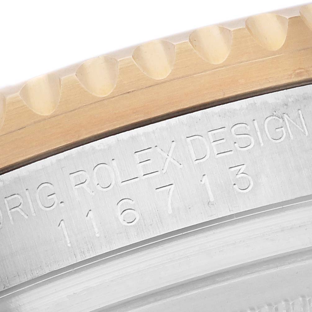 This is a close-up view of the edge and part of the bezel of a Rolex GMT-Master 116713 Men's Steel and Gold (two tone) Black Dial 116713 Men's Steel and Gold (two tone) Black Dial watch, showing the model number engraved.