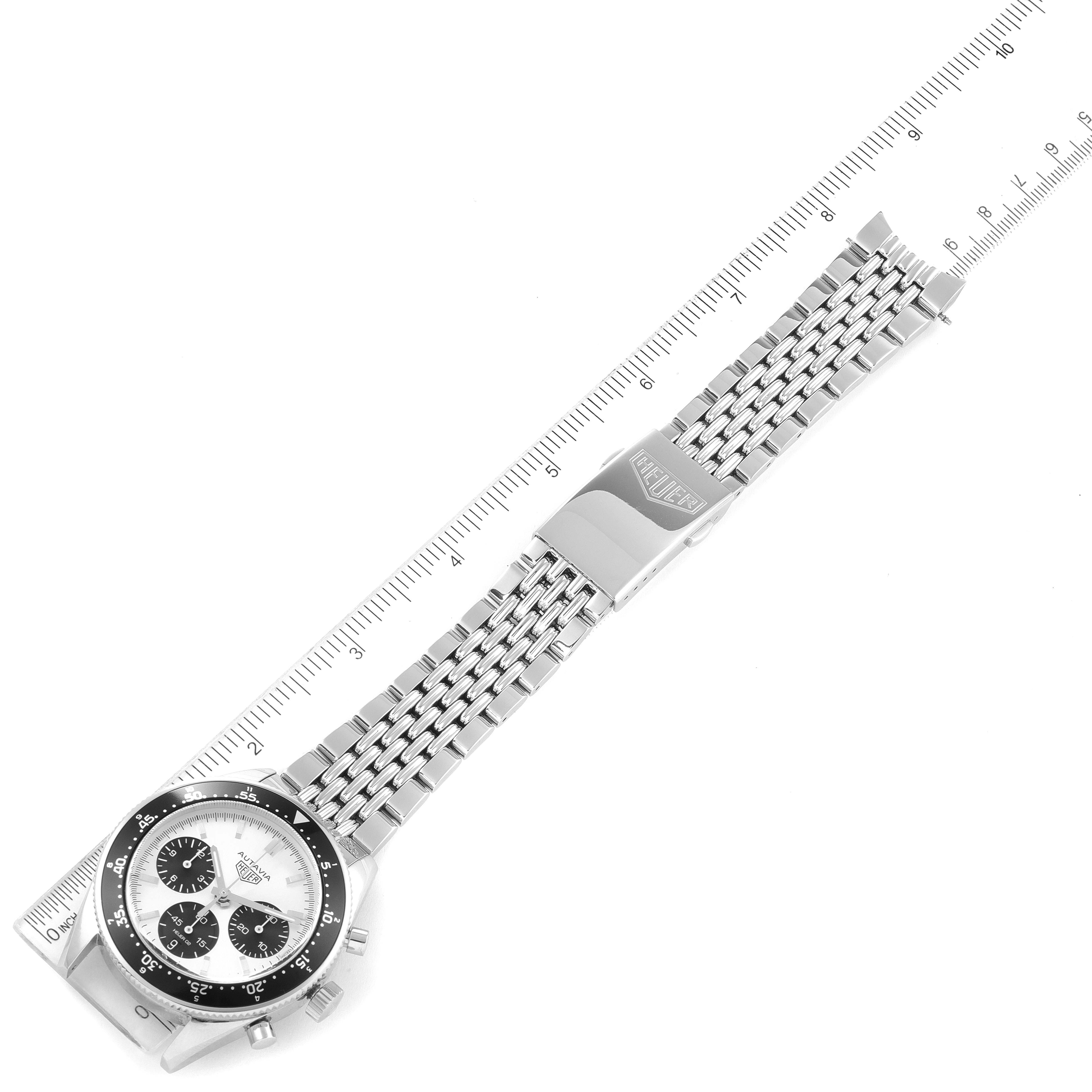 The image shows a Tag Heuer Autavia watch at an angled top-down view, highlighting the dial, bezel, and metal bracelet with a clasp.
