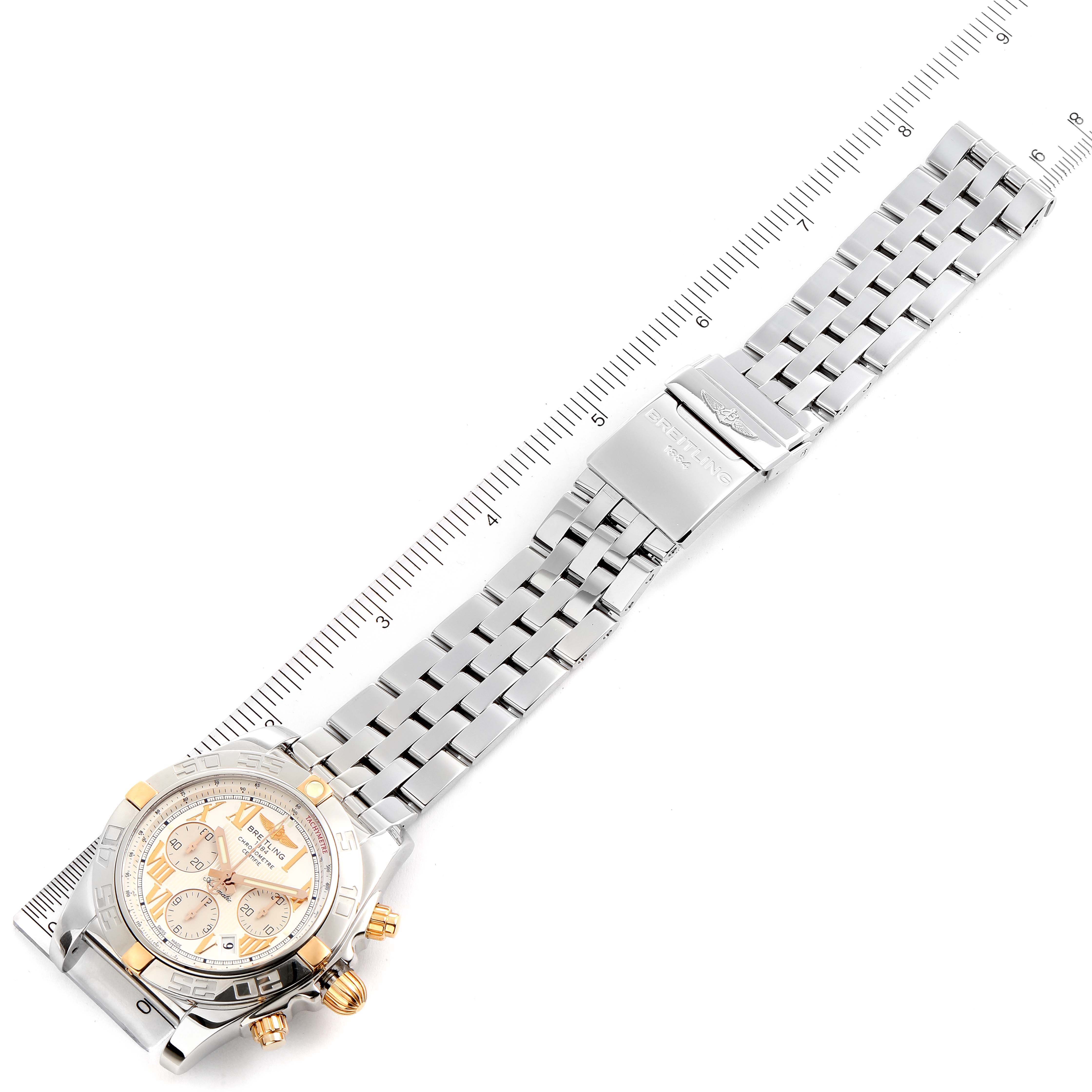 The image shows a Breitling Chronomat IB0110 Men's Stainless Steel Silver Dial IB0110 Men's Stainless Steel Silver Dial watch laid flat with the full bracelet and the dial visible, alongside a measuring scale.