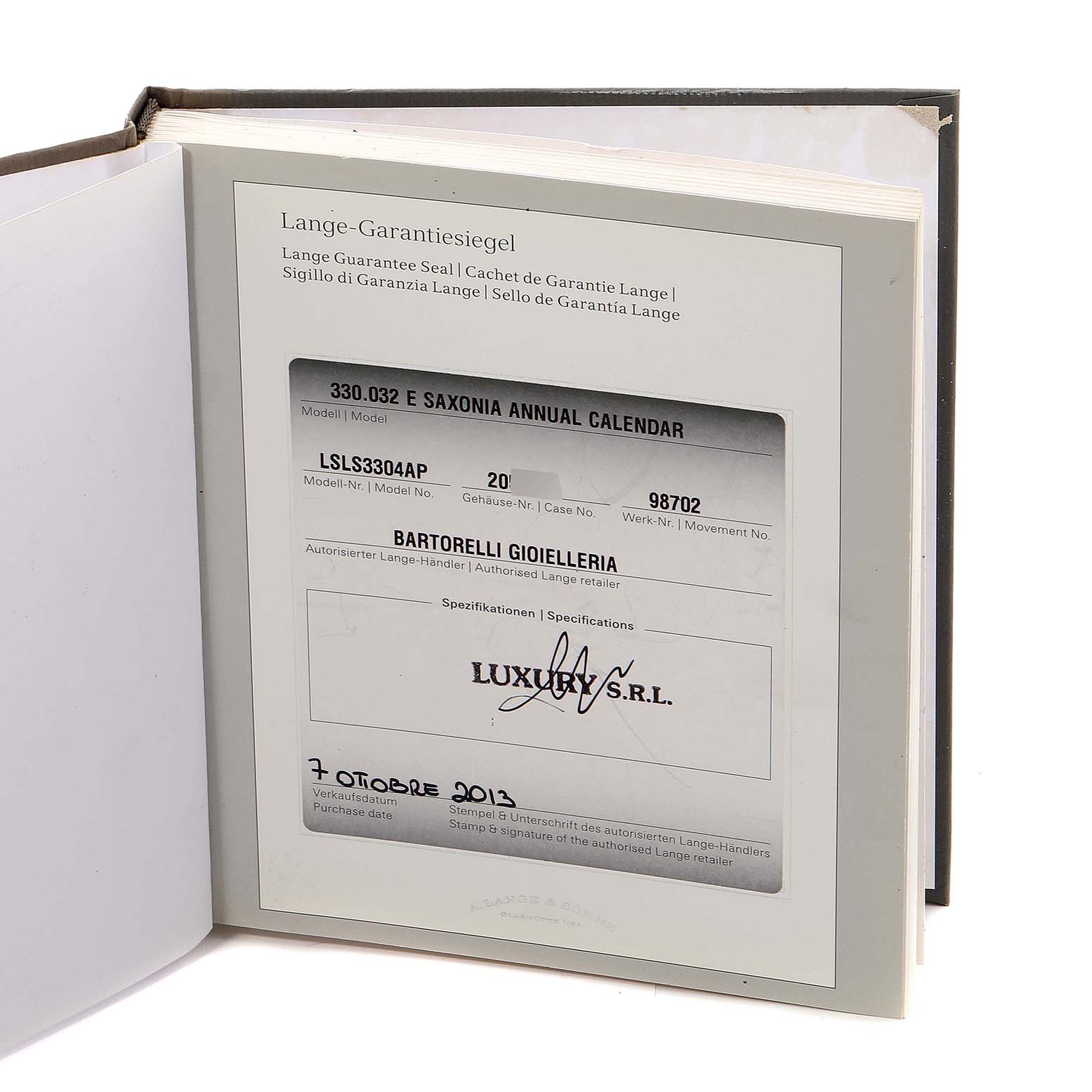 The image displays the warranty booklet for the Saxonia model by A. Lange & Söhne, shown from an angled top-down view.