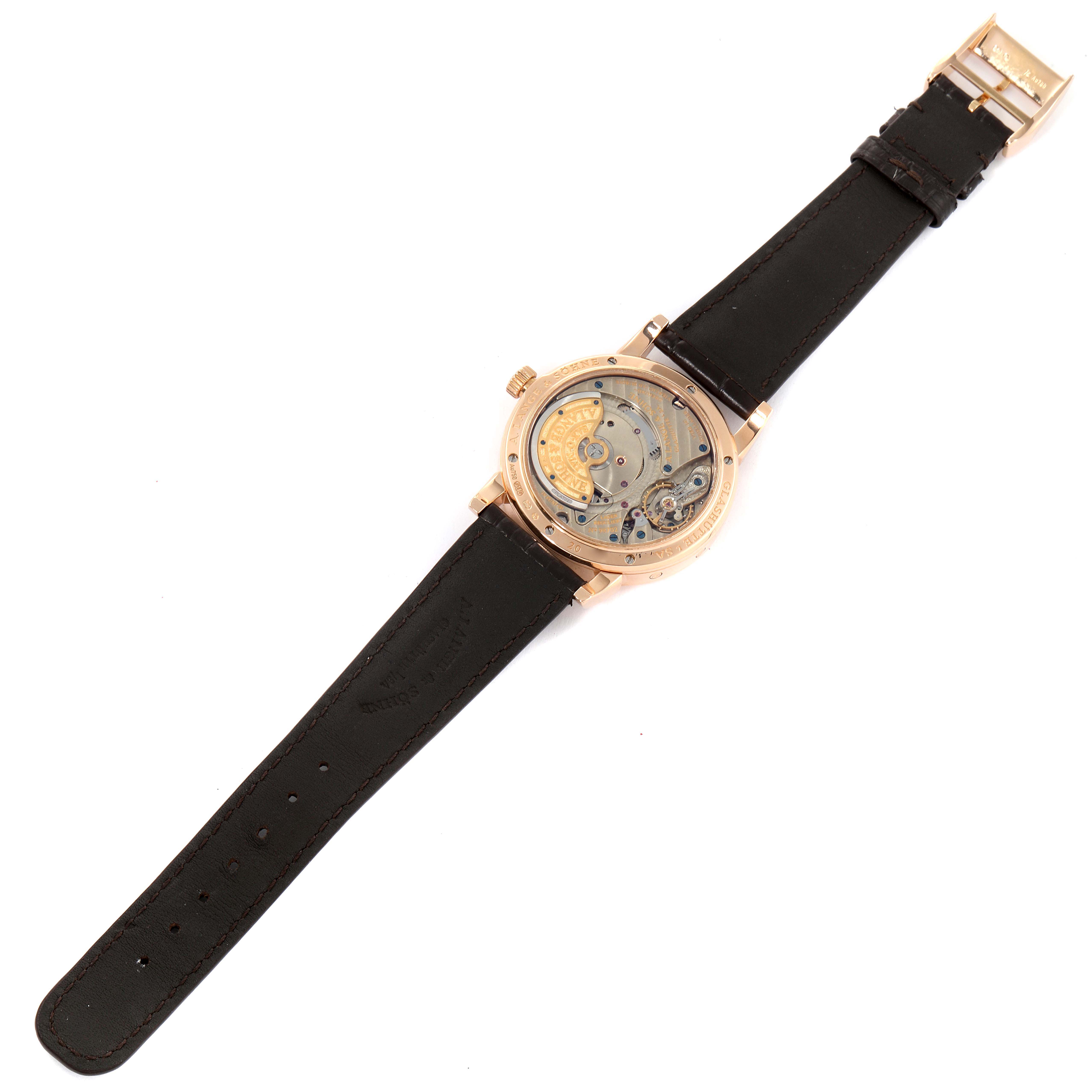 The image shows the back view of an A. Lange & Sohne Saxonia 330.032 Men's Rose Gold Silver Dial watch, highlighting its open movement, black strap, and gold buckle.