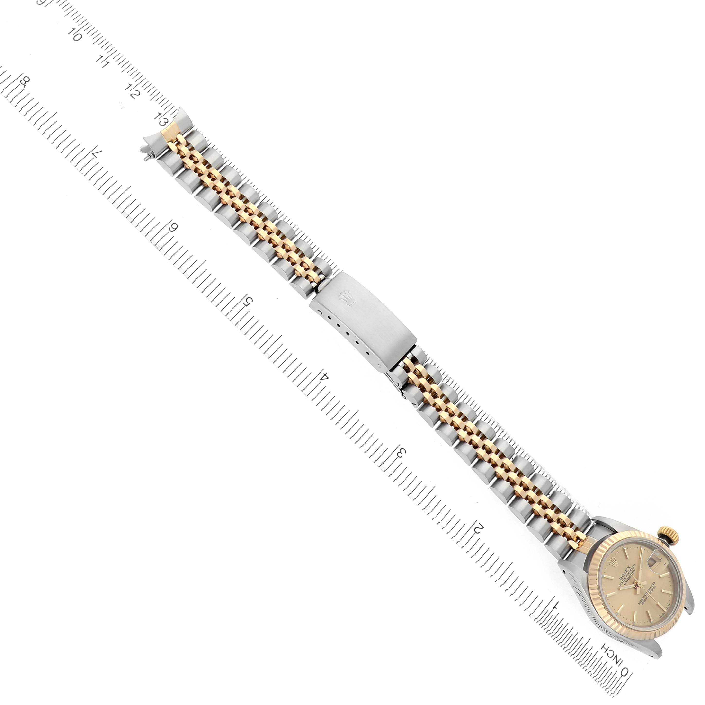 The Rolex Datejust 69173 Women's Steel and Gold (two tone) Champagne Dial 69173 Women's Steel and Gold (two tone) Champagne Dial watch is shown from a top-down angle, displaying the dial, bracelet, and clasp alongside a ruler for scale.