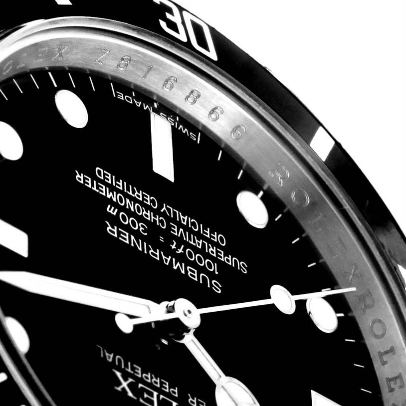 This close-up image of the Rolex Submariner 14060 Men's Stainless Steel Black Dial 14060 Men's Stainless Steel Black Dial watch showcases a segment of its dial, bezel, and part of the hands.