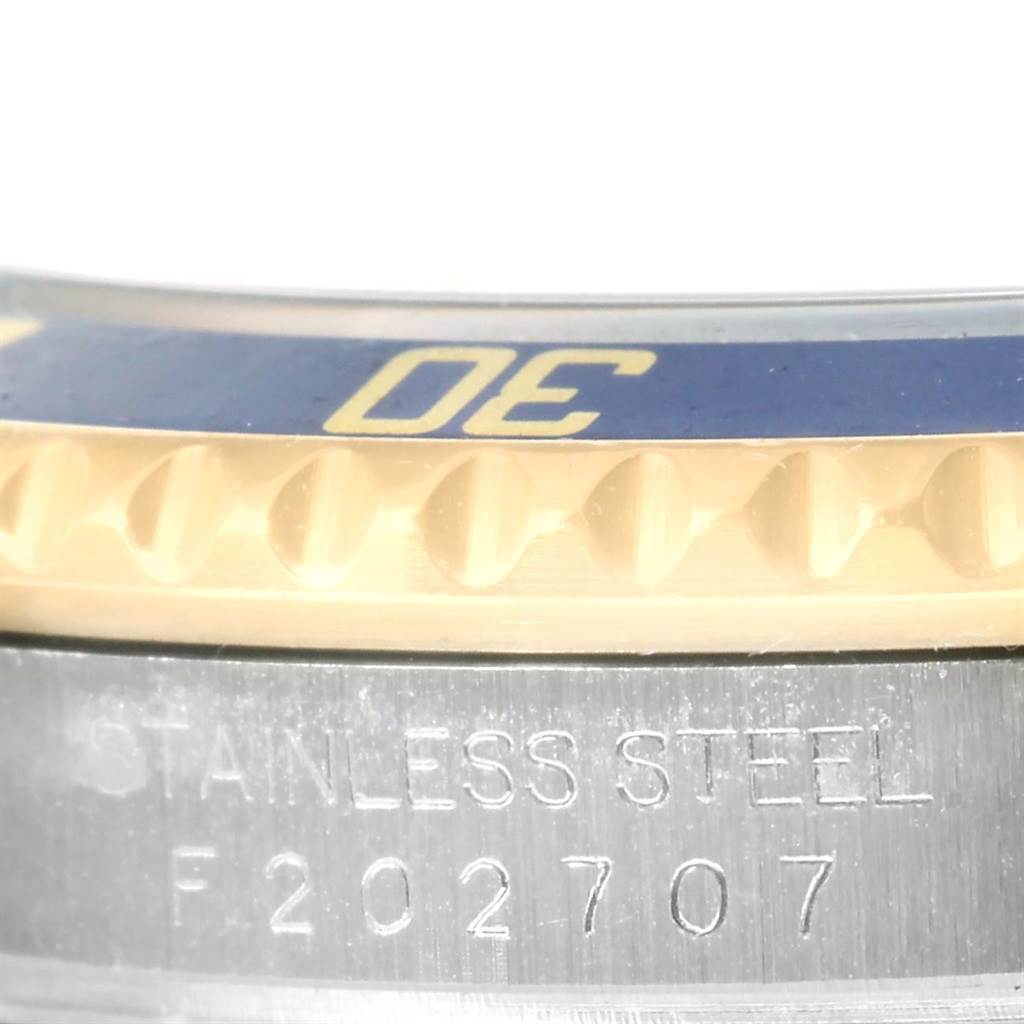 This close-up image of the Rolex Submariner 16613 Men's Steel and Gold (two tone) Blue Dial 16613 Men's Steel and Gold (two tone) Blue Dial shows part of the bezel and the engraved serial number on the stainless steel case.