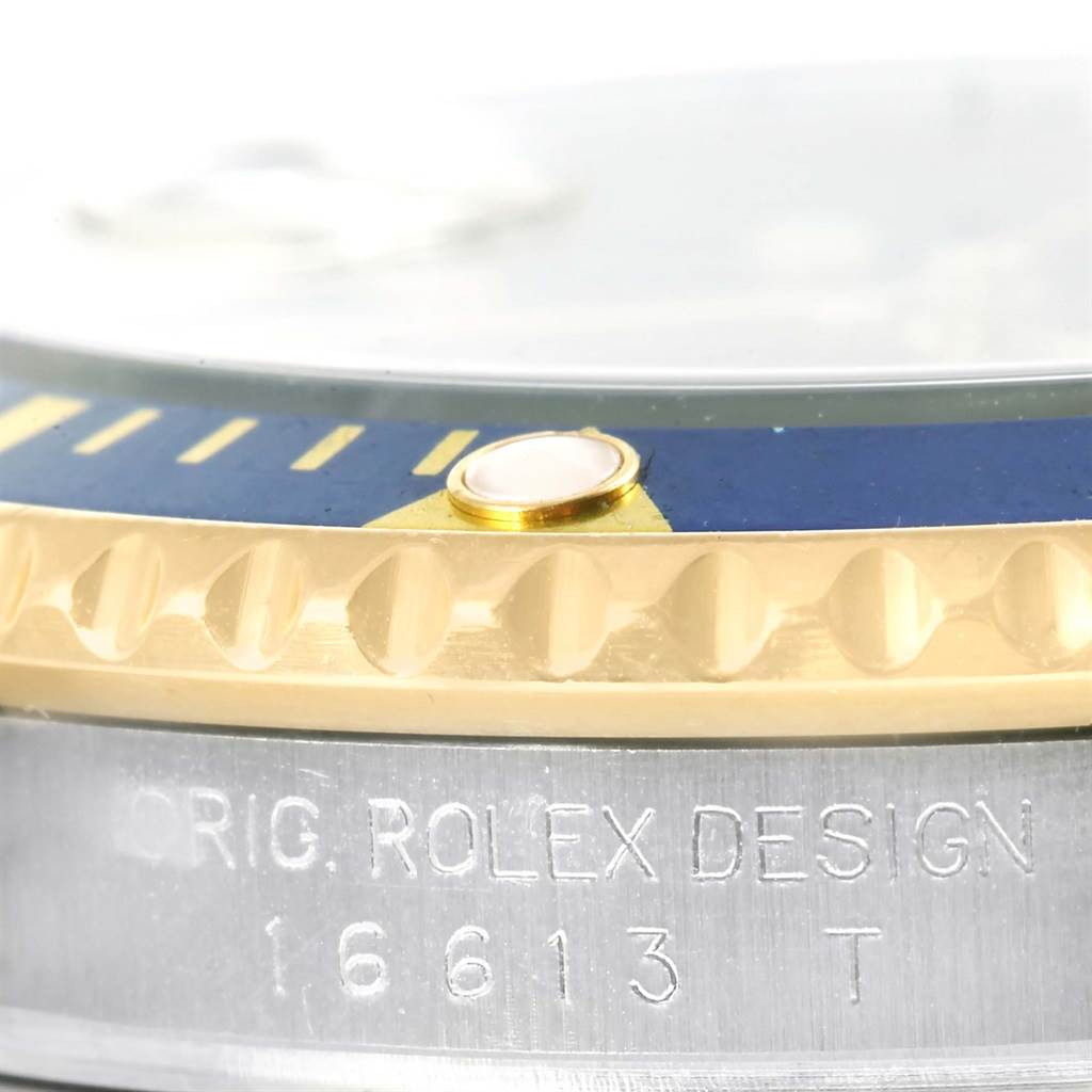 This close-up image of a Rolex Submariner 16613 Men's Steel and Gold (two tone) Blue Dial 16613 Men's Steel and Gold (two tone) Blue Dial watch shows the engraved model number and the edge of the bezel with its detailing.