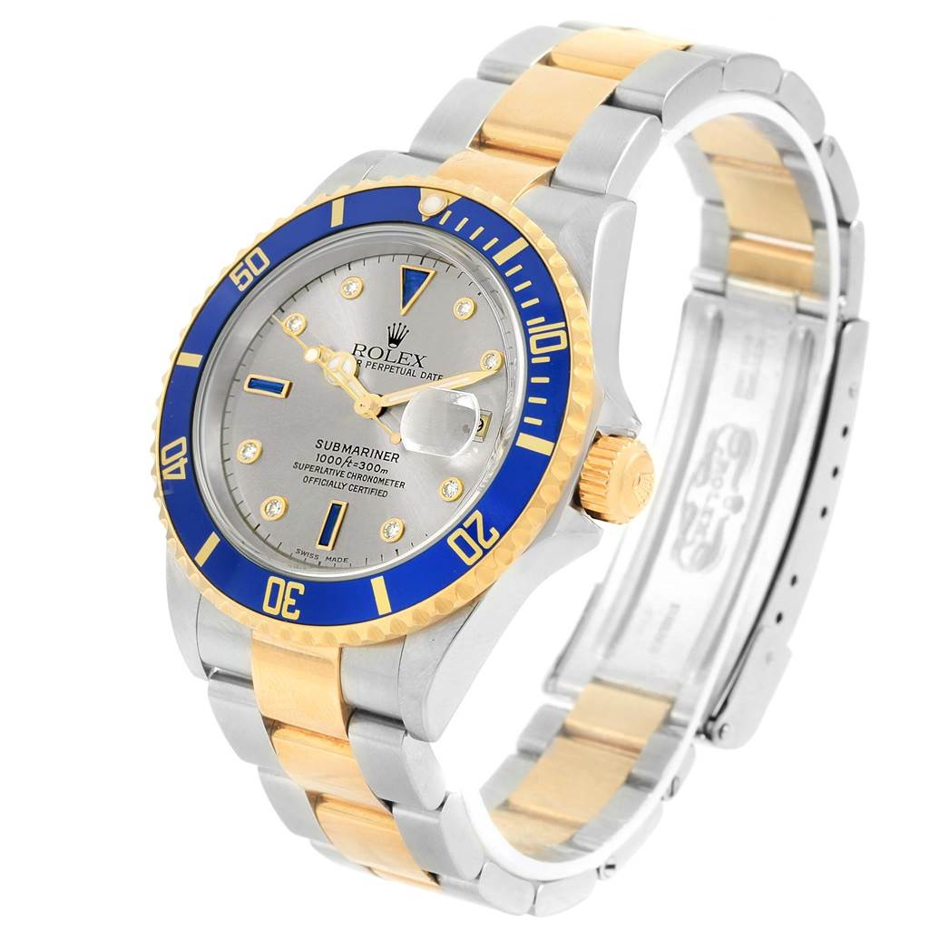 The image shows a Rolex Submariner 16613 Men's Steel and Gold (two tone) Grey Dial 16613 Men's Steel and Gold (two tone) Grey Dial watch at a three-quarter angle, highlighting its two-tone bracelet, blue bezel, and dial.