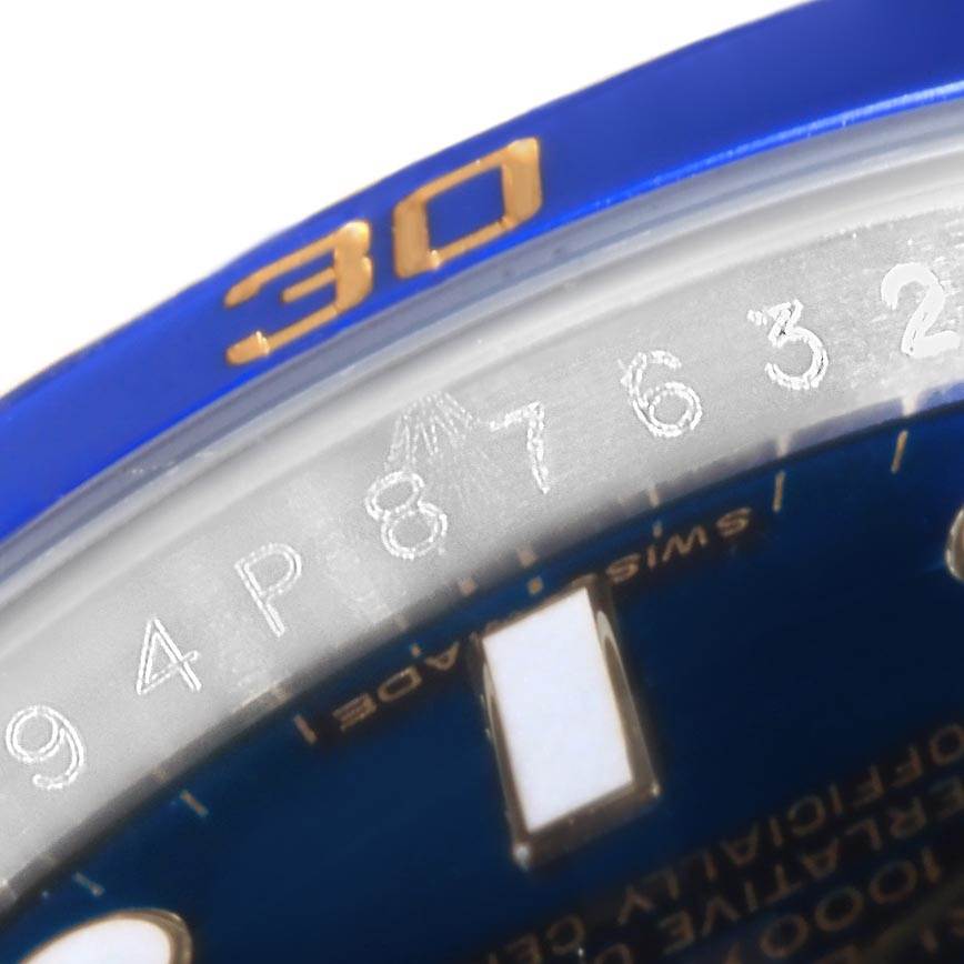 The image shows a close-up angle of the Rolex Submariner 116613 Men's Steel and Gold (two tone) Blue Dial 116613 Men's Steel and Gold (two tone) Blue Dial's bezel, sapphire crystal, and part of the blue dial with luminescent markers.