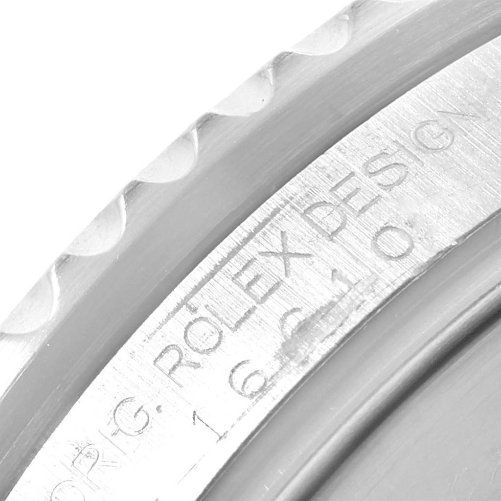 This close-up image of a Rolex Submariner 16610 Men's Stainless Steel Black Dial 16610 Men's Stainless Steel Black Dial shows part of the bezel and the engraved text on the edge of the case.