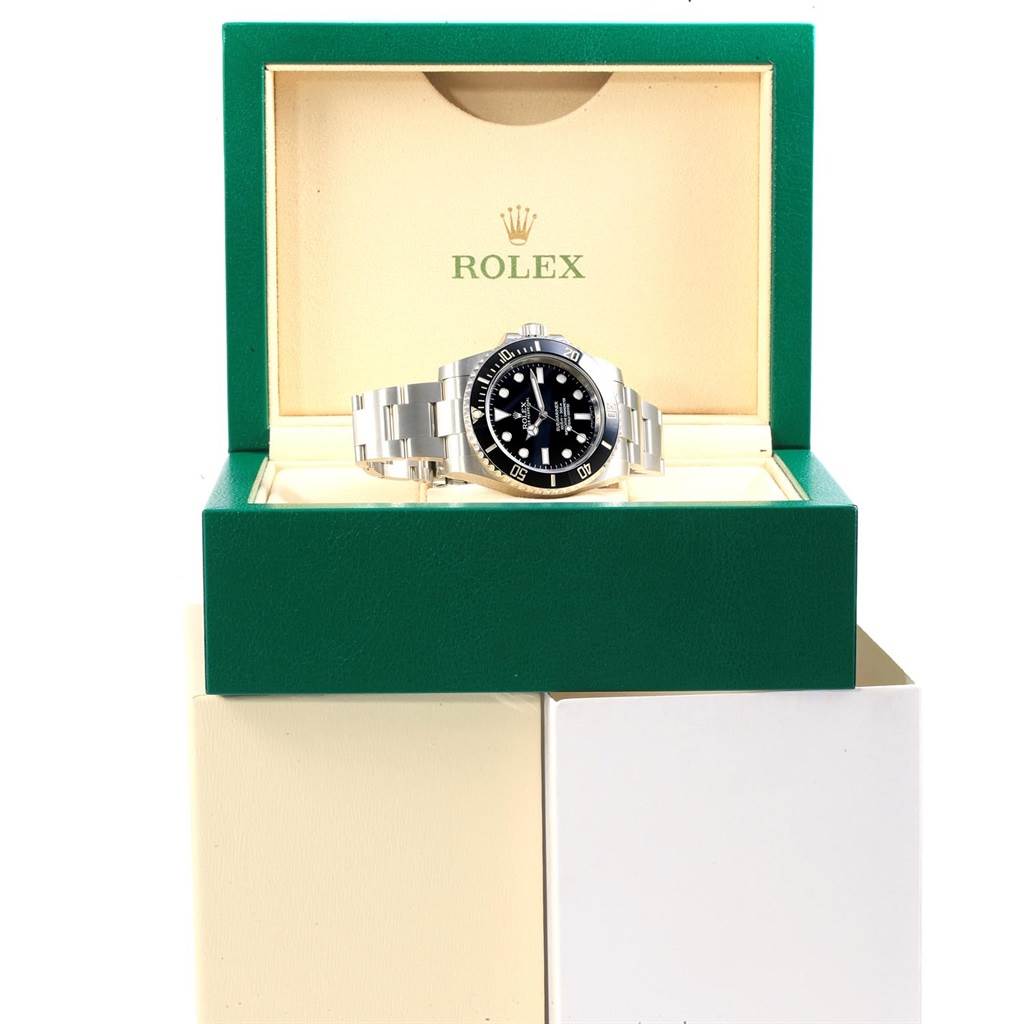 The Rolex Submariner 114060 Men's Stainless Steel Black Dial 114060 Men's Stainless Steel Black Dial watch is shown from a front angle inside its green and beige box, displaying the face and bracelet.