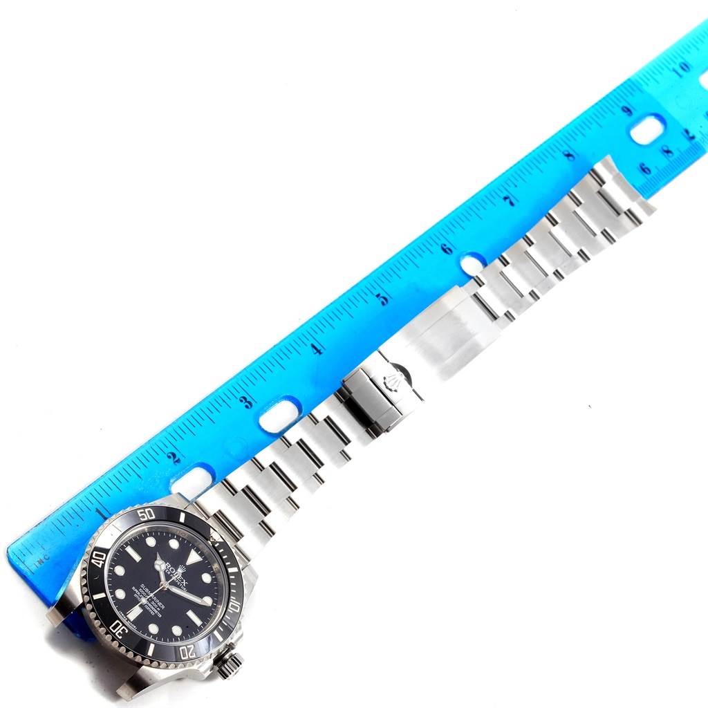 The image shows a Rolex Submariner 114060 Men's Stainless Steel Black Dial 114060 Men's Stainless Steel Black Dial watch at a top-down angle next to a ruler, displaying its face, bezel, and bracelet.