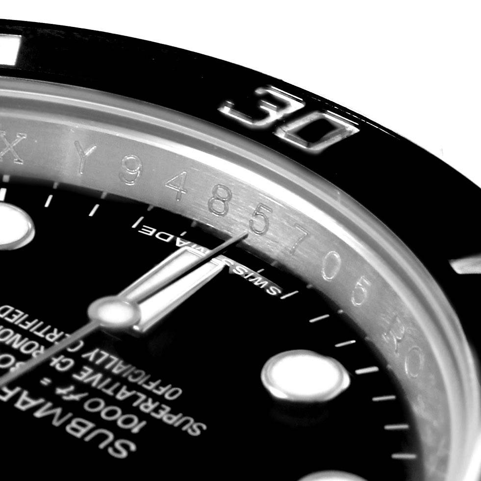 The image shows a close-up angle of a Rolex Submariner 114060 Men's Stainless Steel Black Dial 114060 Men's Stainless Steel Black Dial watch, highlighting the bezel, minute hand, and part of the dial with markers.