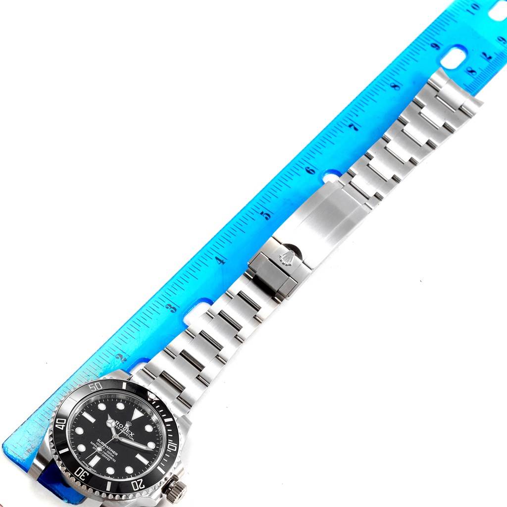 The image shows a Rolex Submariner 114060 Men's Stainless Steel Black Dial 114060 Men's Stainless Steel Black Dial watch lying flat with its bracelet extended, next to a blue ruler.