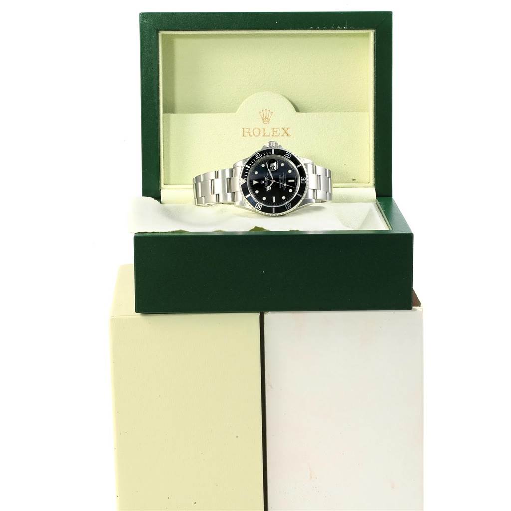 The Rolex Submariner 16610 Men's Stainless Steel Black Dial 16610 Men's Stainless Steel Black Dial watch is displayed inside its green and cream box at a front angle.