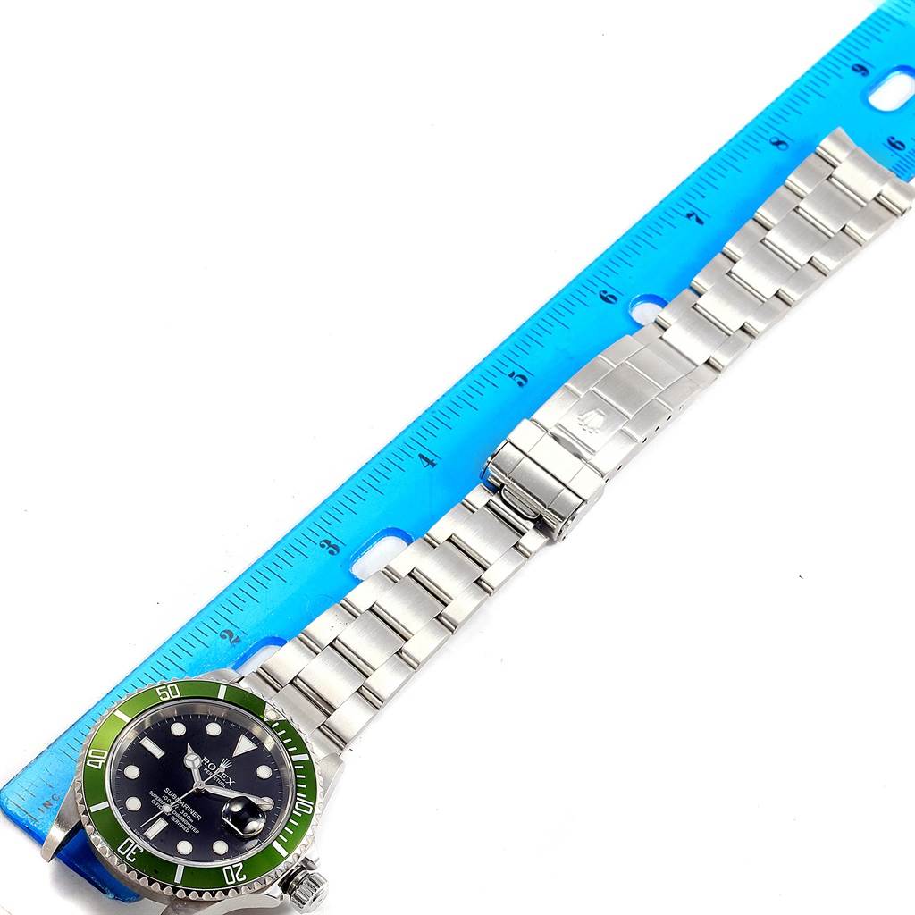 The image shows a top-down view of a Rolex Submariner 16610LV Men's Stainless Steel Black Dial 16610LV Men's Stainless Steel Black Dial watch, displaying the full length, bracelet, and clasp next to a blue ruler.