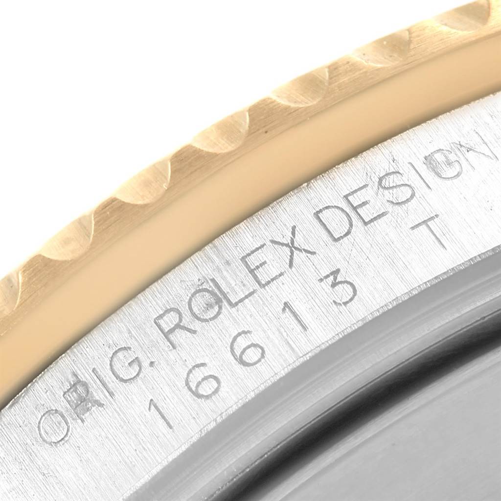 The image shows a close-up of the Rolex Submariner 16613 Men's Steel and Gold (two tone) Grey Dial 16613 Men's Steel and Gold (two tone) Grey Dial model bezel and case side with engraved inscriptions.