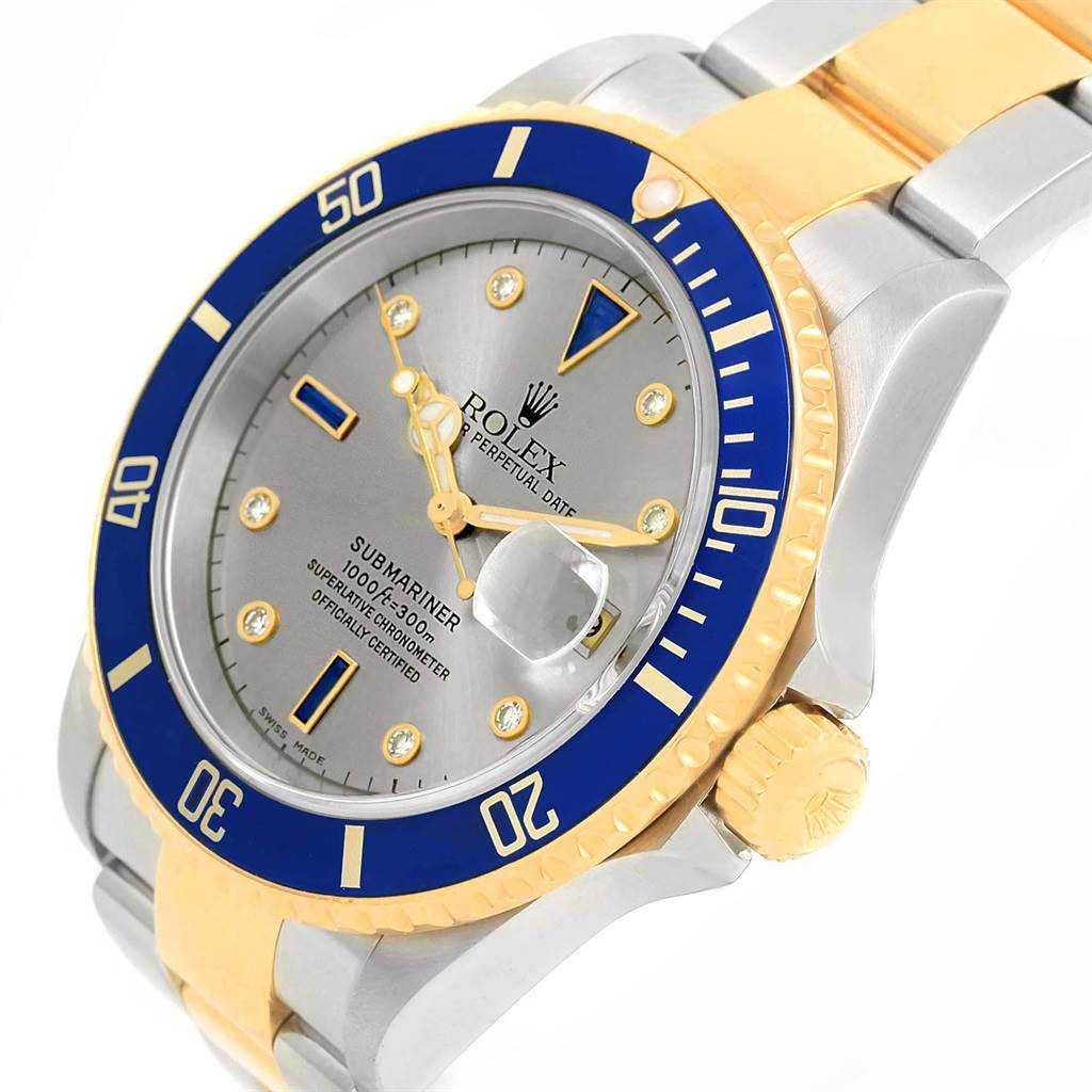 The image shows a Rolex Submariner 16613 Men's Steel and Gold (two tone) Grey Dial 16613 Men's Steel and Gold (two tone) Grey Dial watch from a three-quarter angle, highlighting its blue bezel, gold and silver band, and face details.