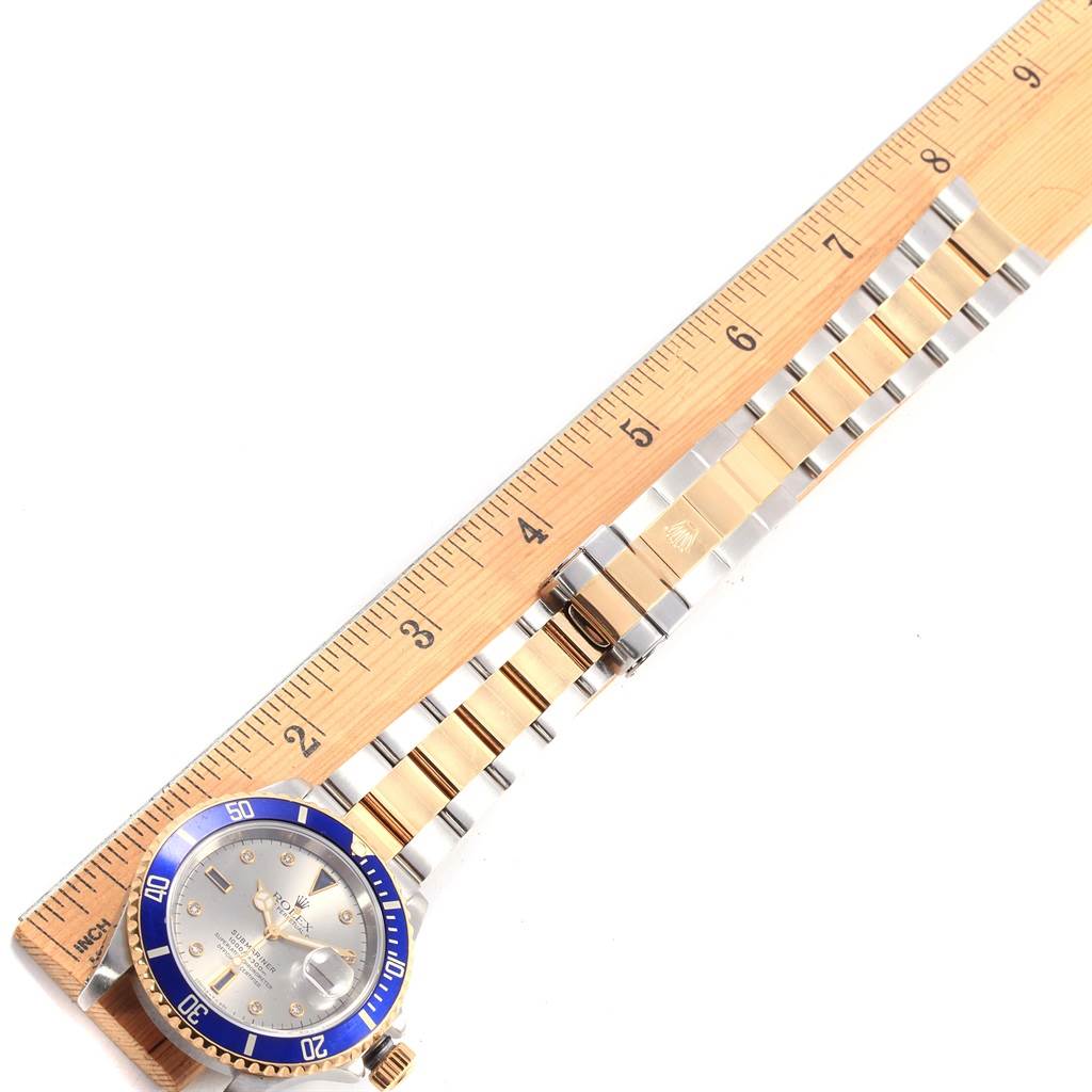 The angle shows the full length of the Rolex Submariner 16613 Men's Steel and Gold (two tone) Grey Dial 16613 Men's Steel and Gold (two tone) Grey Dial watch, with the face and bracelet laid next to a ruler.