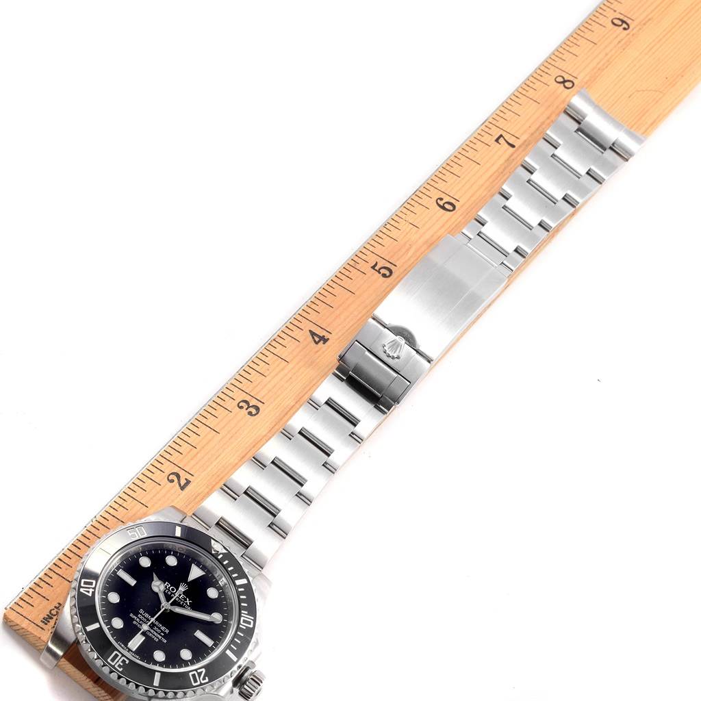 The image shows a Rolex Submariner 114060 Men's Stainless Steel Black Dial 114060 Men's Stainless Steel Black Dial model watch and its stainless steel bracelet laid next to a wooden ruler.