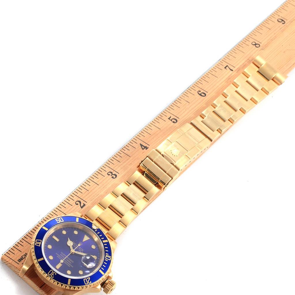The image shows a top view of a Rolex Submariner 16618 Men's Yellow Gold Purple Dial 16618 Men's Yellow Gold Purple Dial watch, highlighting its strap, clasp, and part of the dial, alongside a ruler for size reference.