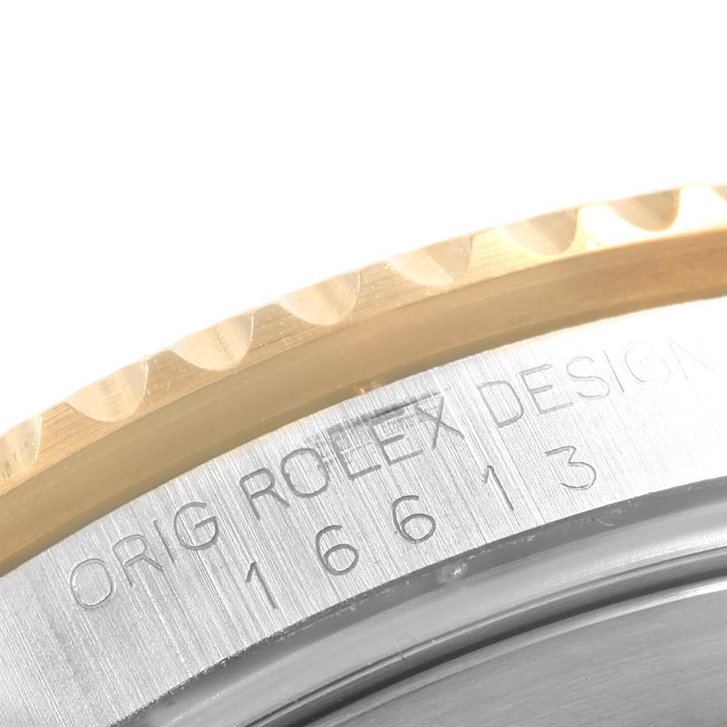 This image shows a close-up of the edge of the case and bezel of a Rolex Submariner 16613 Men's Steel and Gold (two tone) Black Dial 16613 Men's Steel and Gold (two tone) Black Dial with its engraved model number.