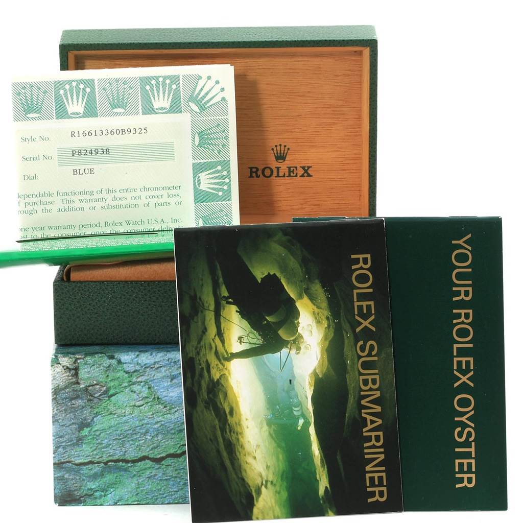 The image shows a Rolex Submariner 16613 Men's Steel and Gold (two tone) Blue Dial 16613 Men's Steel and Gold (two tone) Blue Dial's box, warranty card, and manuals, viewed from the front.